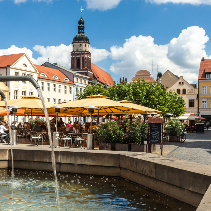 Lokal: Der Cottbuser Altmarkt in der Lausitz, im Vordergrund der Brunnen, im Hintergrund der Altmarkt bei Sommer und die Oberkirche.