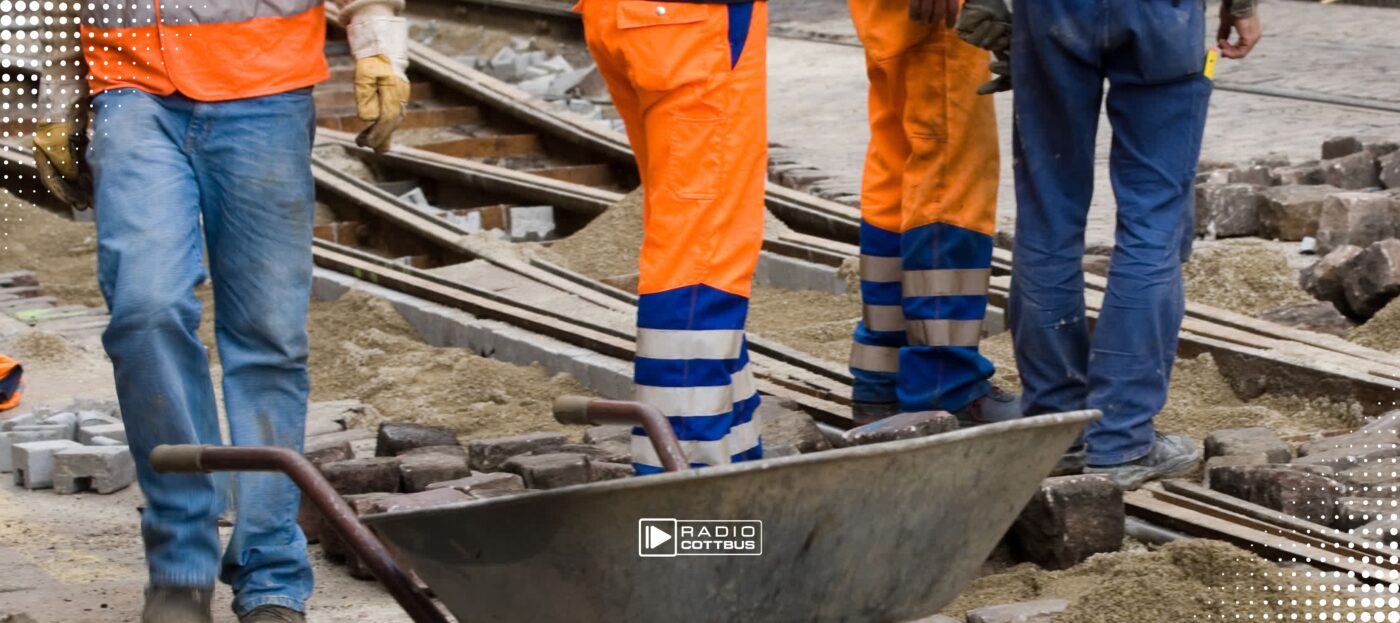 4 Männer stehen auf einer Baustelle und arbeiten an Gleisen