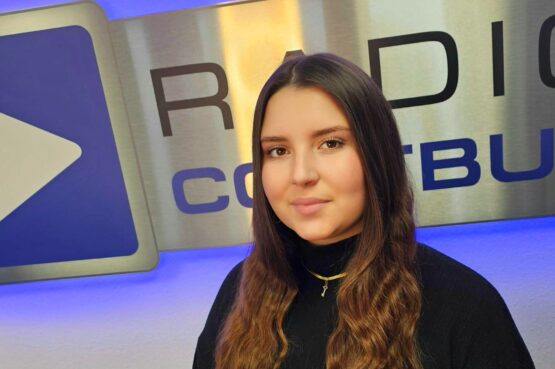 Dena Nowak Media Beraterin Dena Nowak vor dem Logo von Radio Cottbus im November 2024