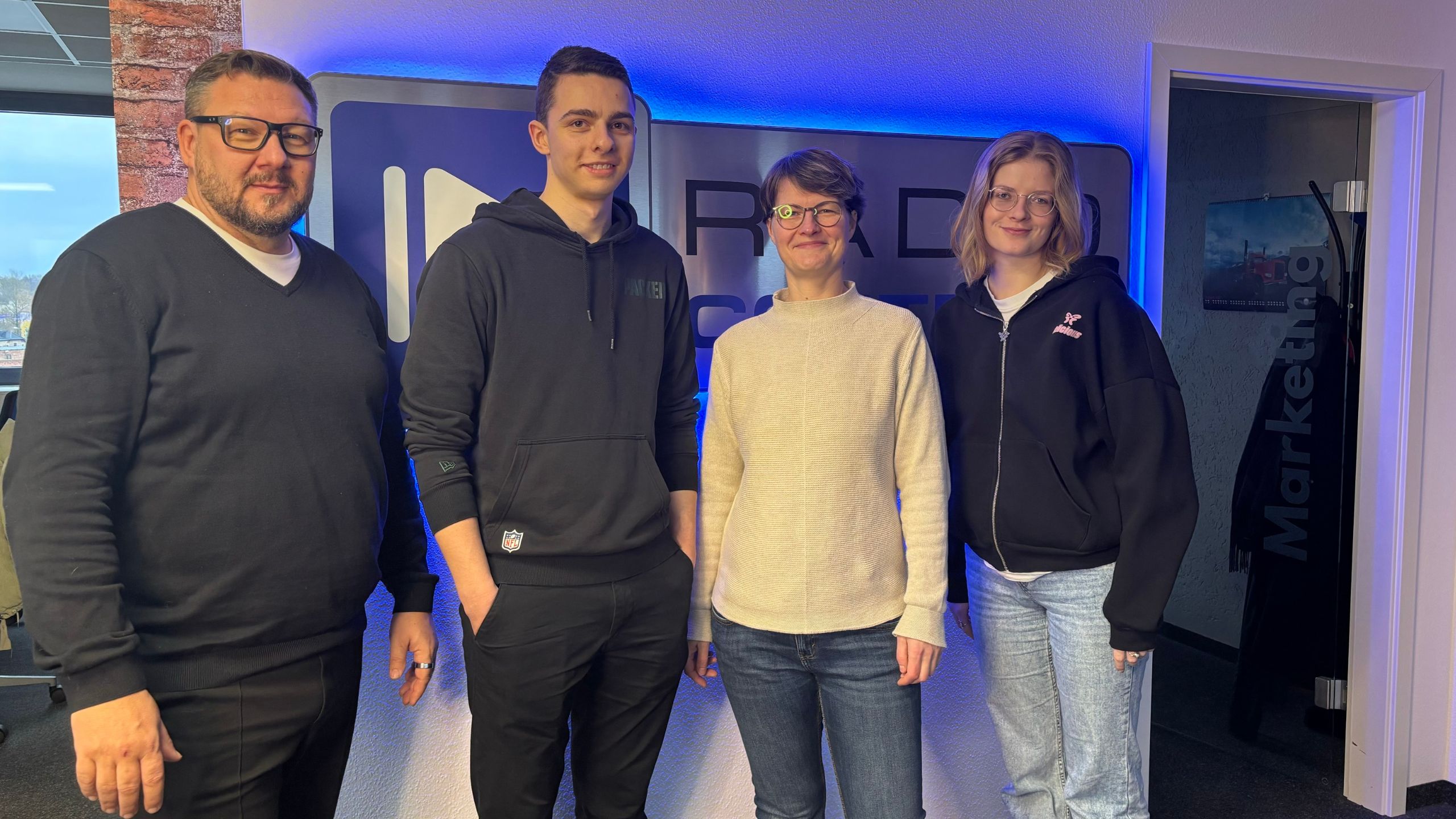 Roxana und Felix vom Cottbuser Acapella Chor Popkon stehen mit Ronny Gersch und Luka Stadelmeier im Studio von Radio Cottbus im November 2024