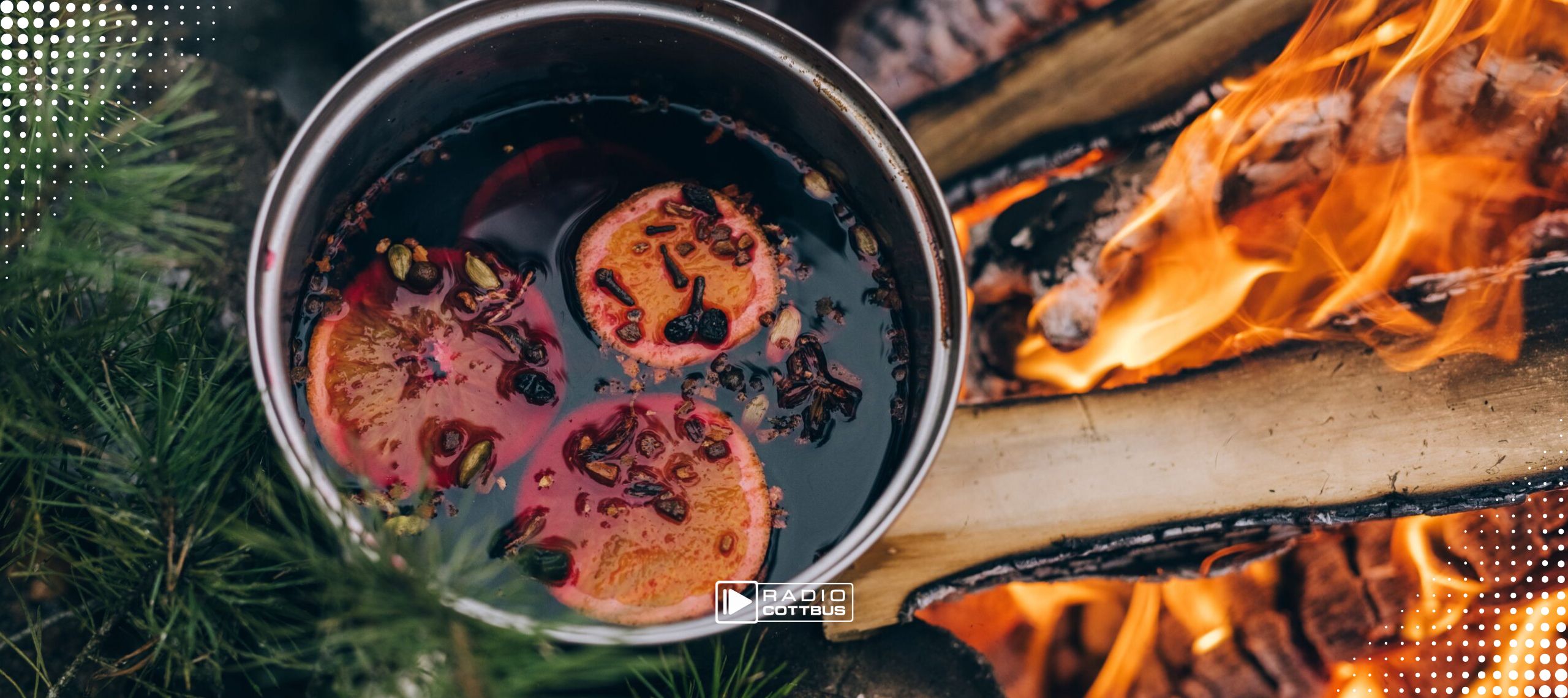 Ein Top mit Glühwein steht über einem Lagerfeuer.