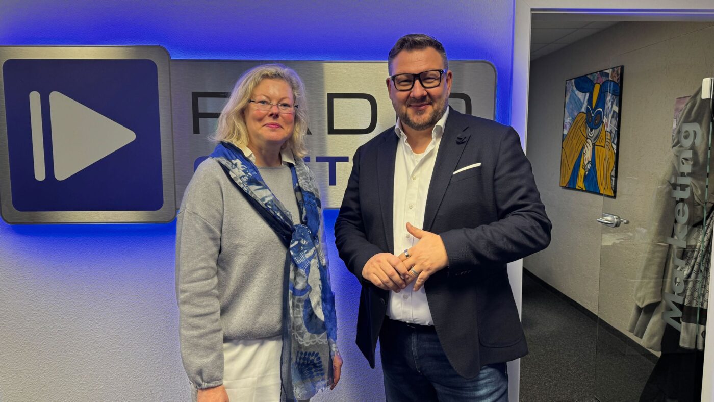 Kerstin Micka und Ronny Gersch vor dem Radio Cottbus Logo