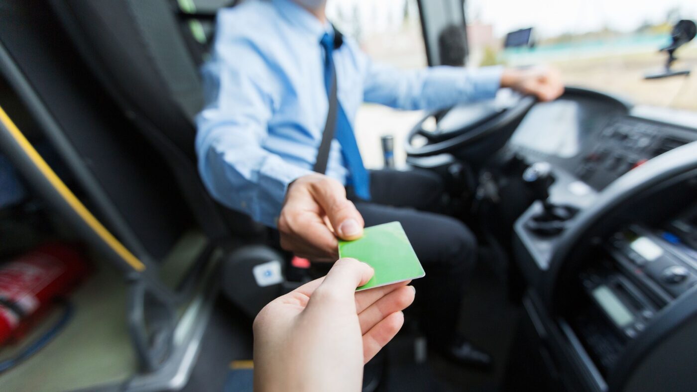 Ein grünes Ticket wird im Bus an den Fahrer übergeben.