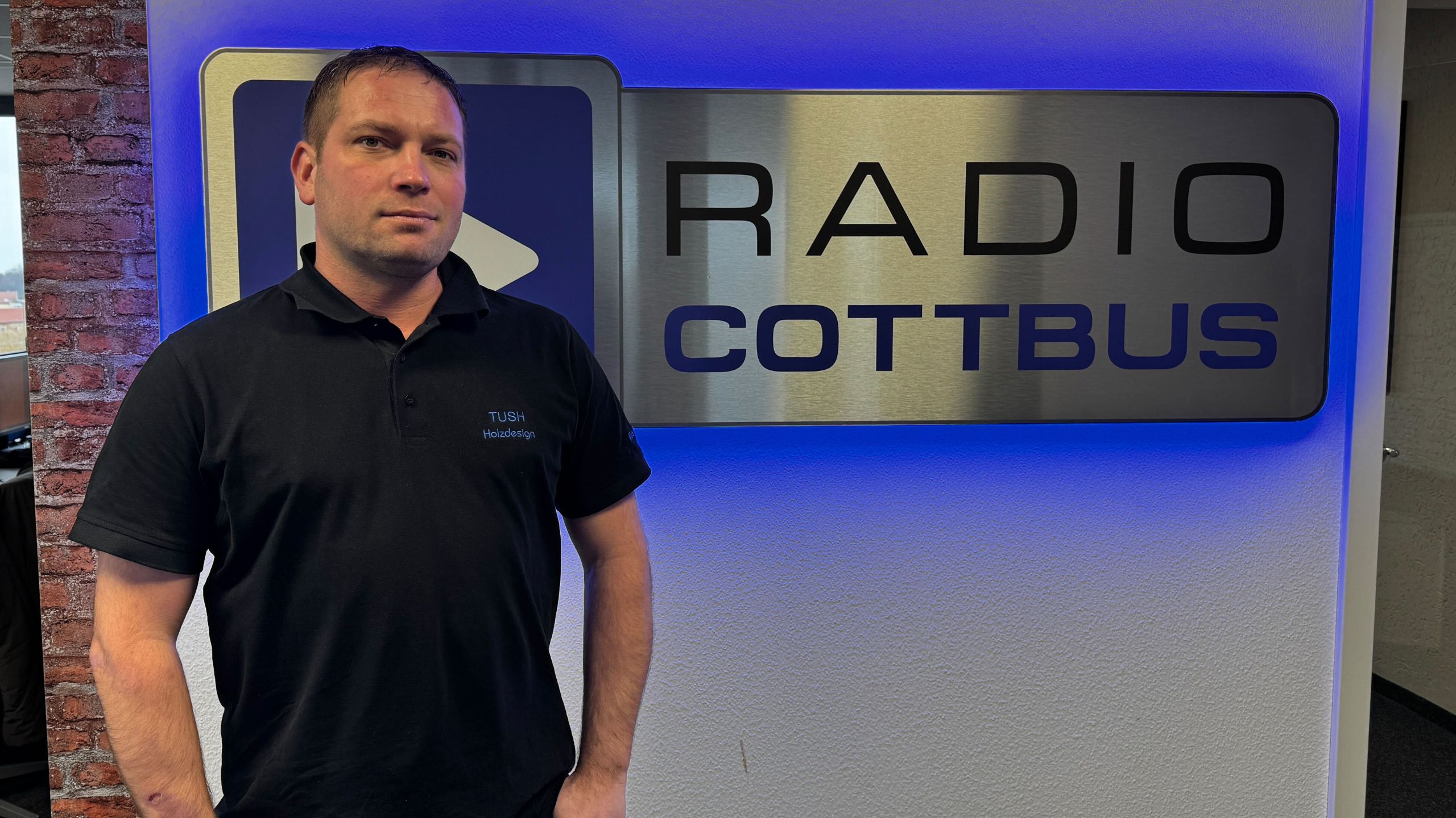 Toni Hannusch von TUSH Holzdesign vor dem Radio Cottbus Logo