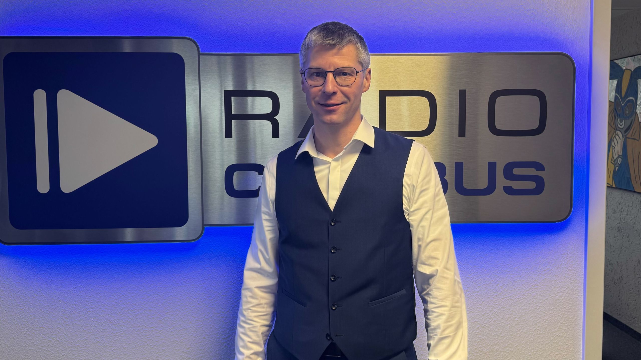Henrik Ansorge von der Stiftung Lausitzer Braunkohle vor dem Radio Cottbus Logo