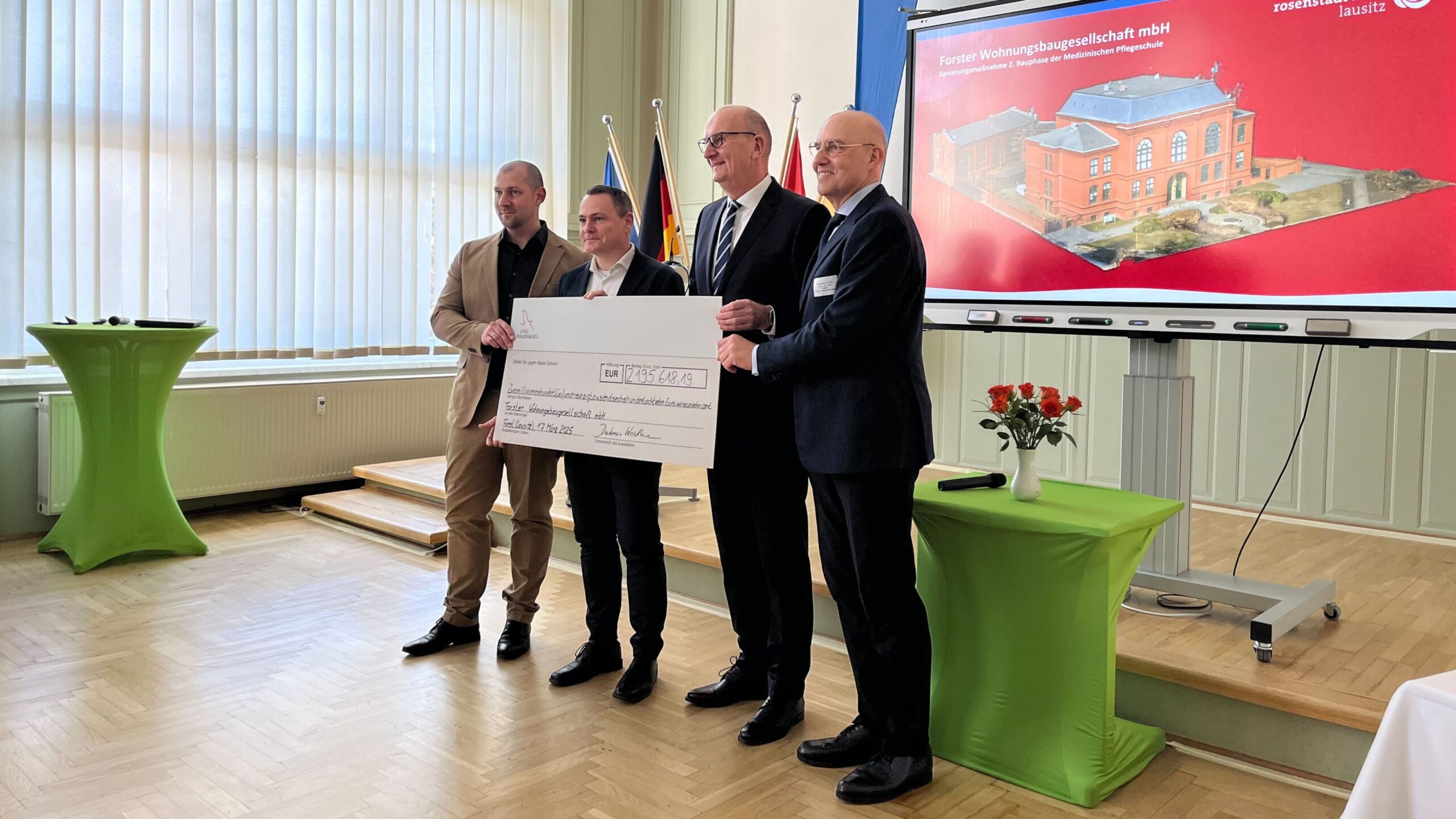 Robert Richter von der Forster Wohnungsbaugesellschaft neben Brandenburgs Ministerpräsident Dietmar Woidke und MUL-CT Vorstand Prof. Eckhard Nagel in der Pflegeschule Forst bei der Scheckübergabe