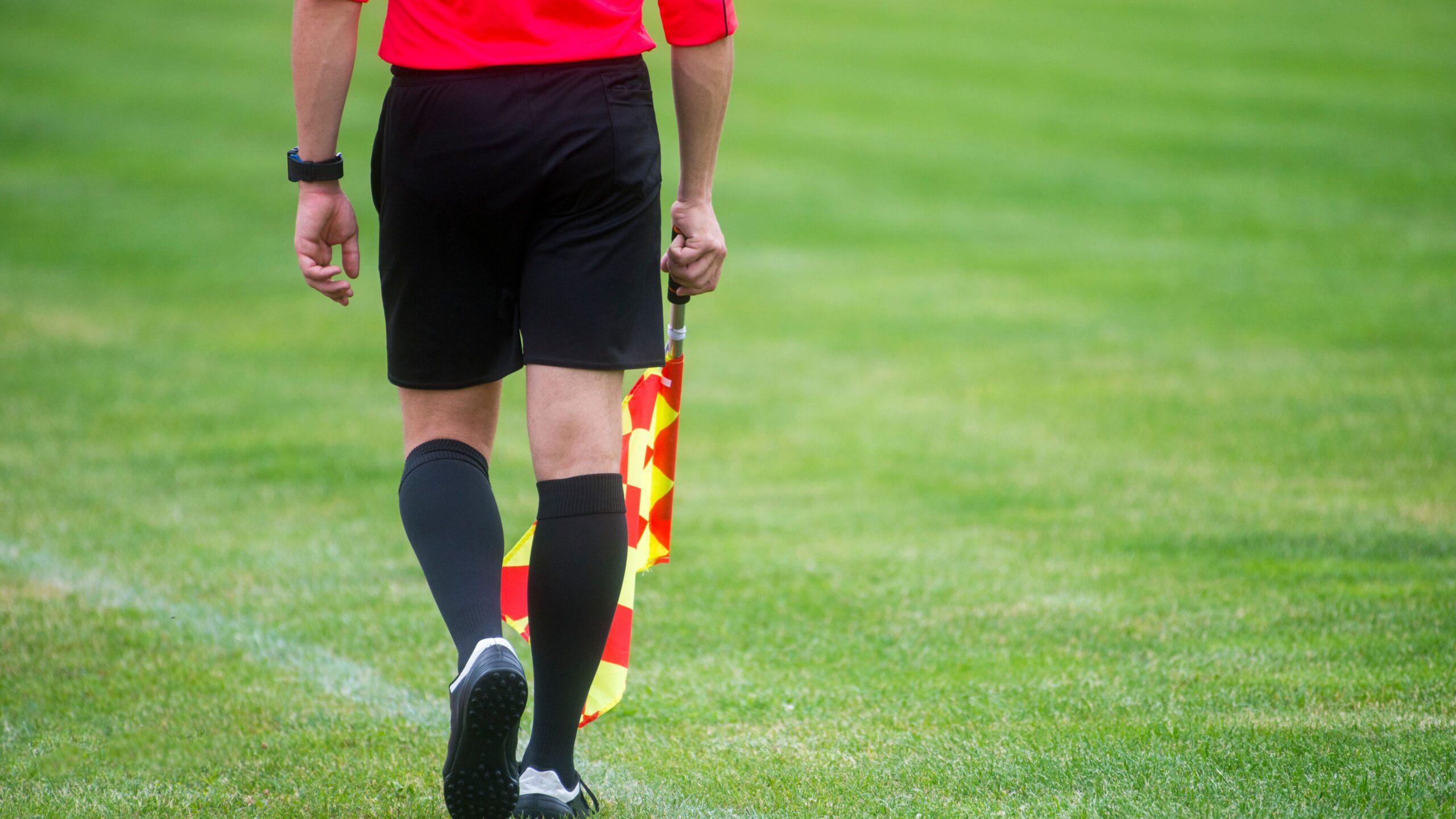 Ein Linienrichter beim Fußball mit einer Abseitsfahne in der Hand