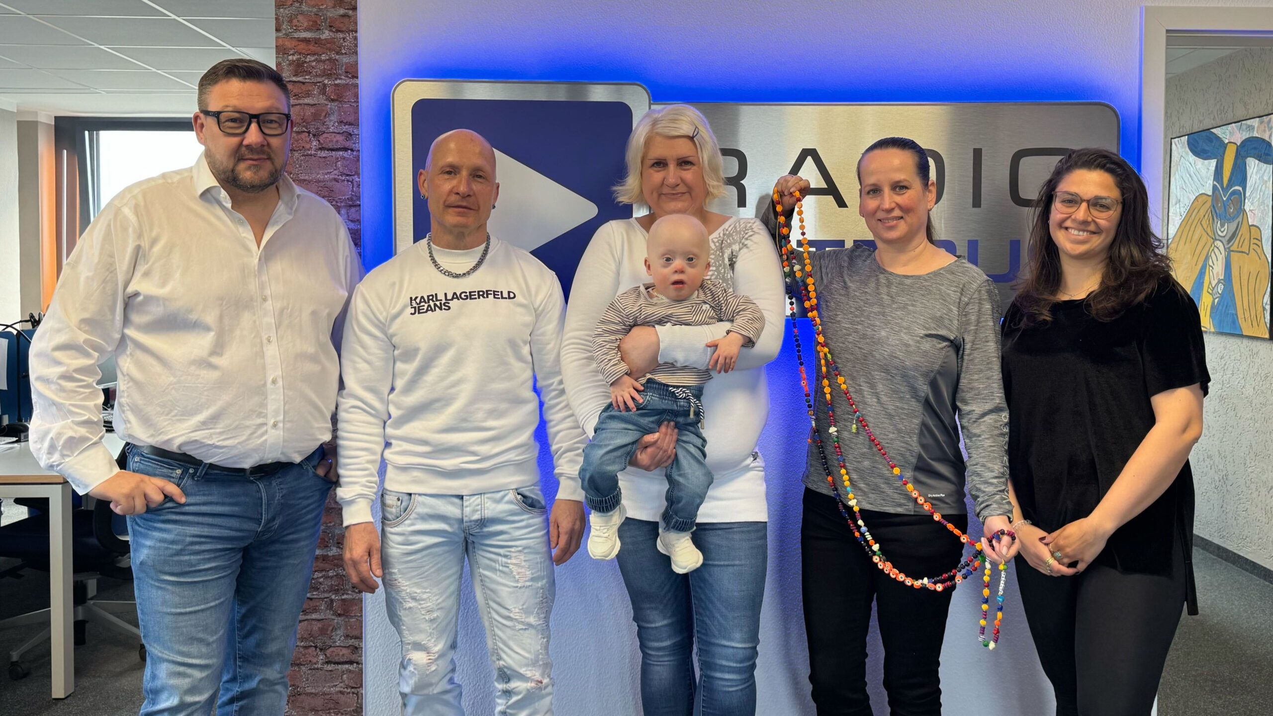 Die Radio Cottbus Wacher Macher mit Xanthos, seinen Eltern und Manja Koal vor dem Radio Cottbus Logo