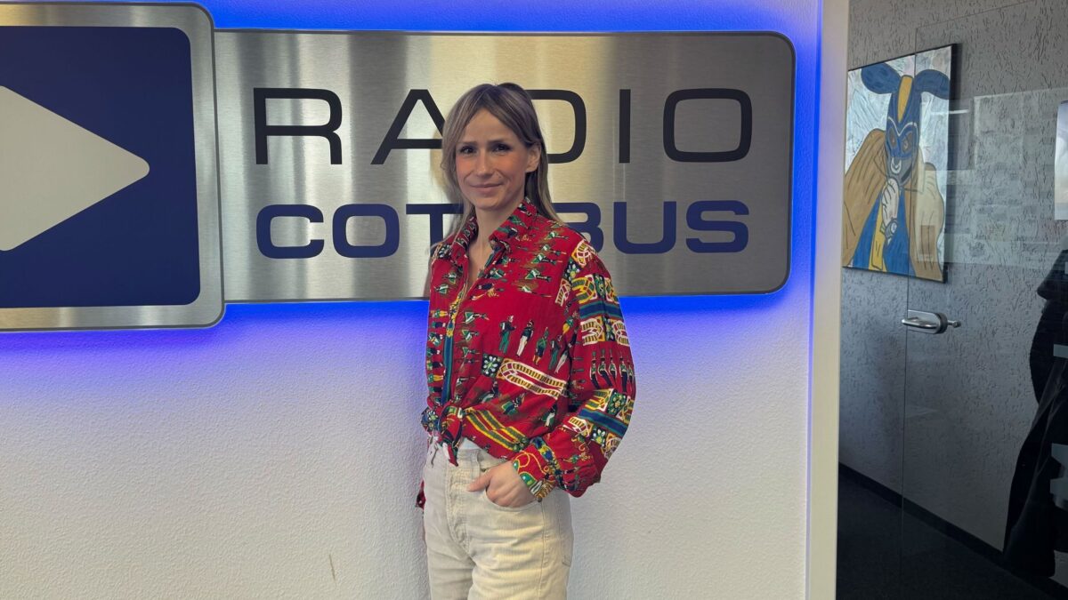 Chefin on Air Carolin Puscha vor dem Radio Cottbus Logo