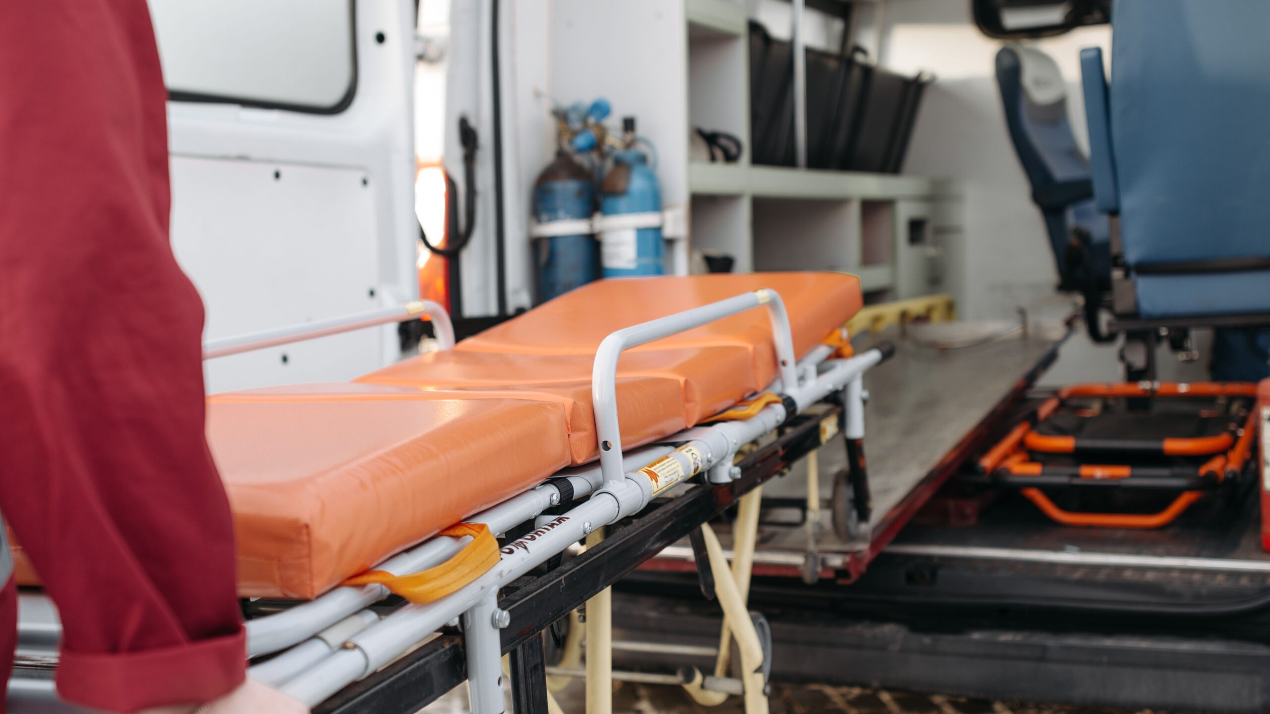 Ein Rettungssanitäter schiebt eine Rettungstrage in einen offenen Krankenwagen