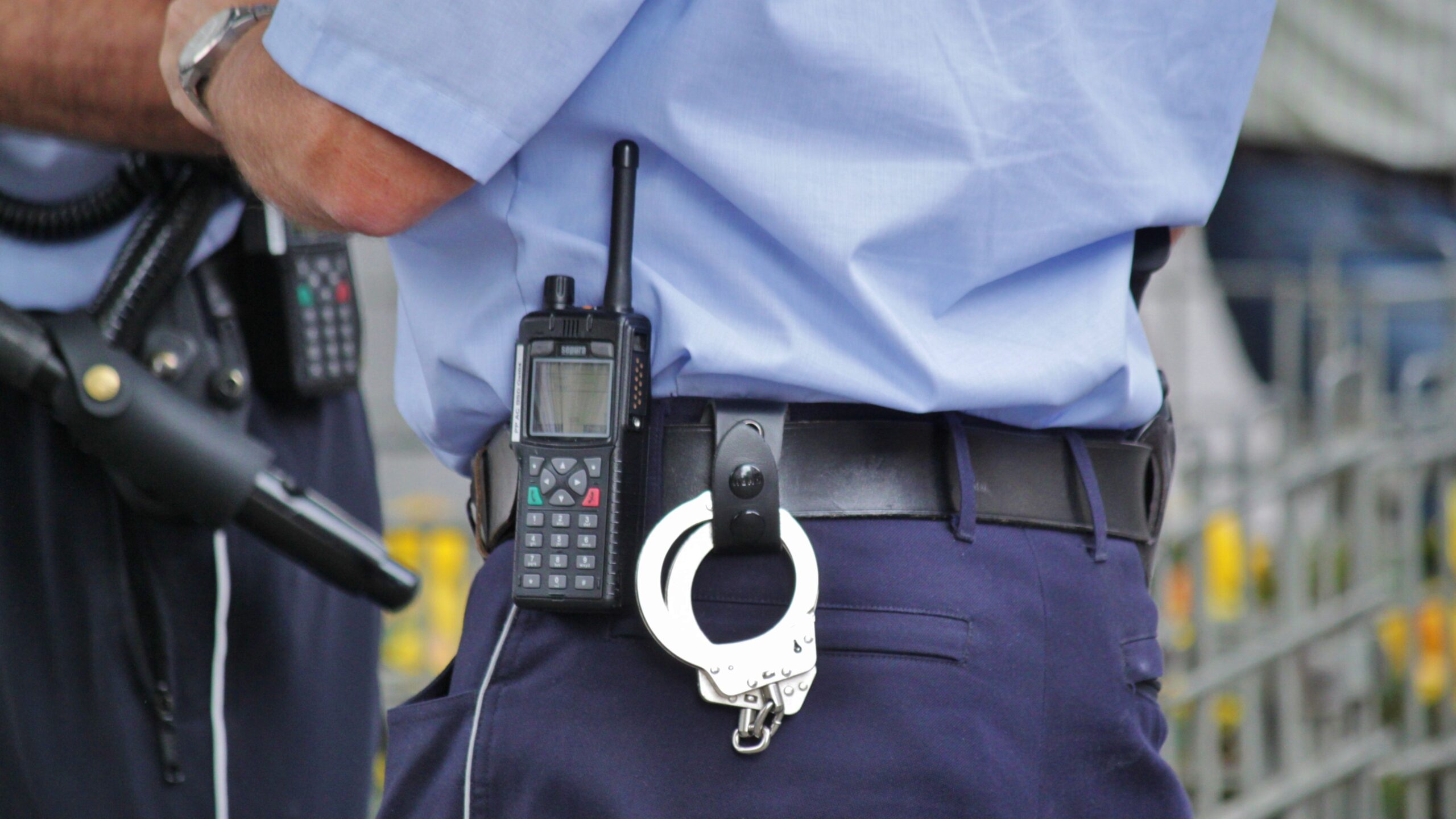 Ein Polizist von hinten, an seinem Gürtel hängen Handschellen und ein Funkgerät