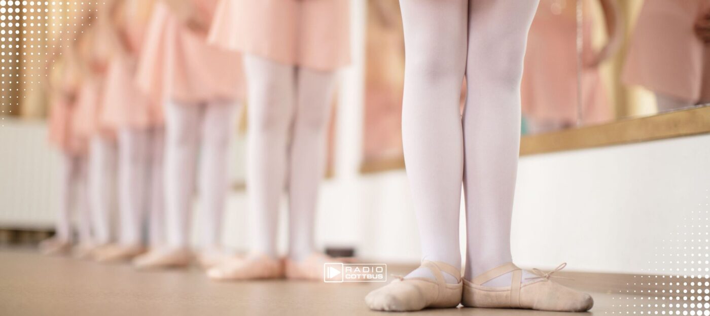 Mehrere kleine Mädchen stehen hintereinander an der Ballettstange und tragen Ballettschuhe