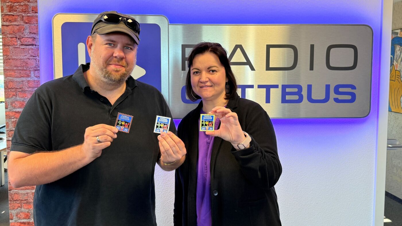 Falk Pinkwart von den Cottbuser Geocachern und seine Frau vor dem Radio Cottbus Logo