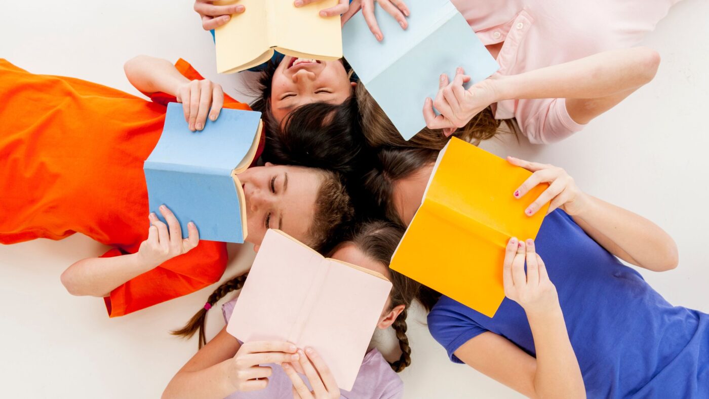 Kinder liegen im Kreis auf dem Boden und lesen Bücher