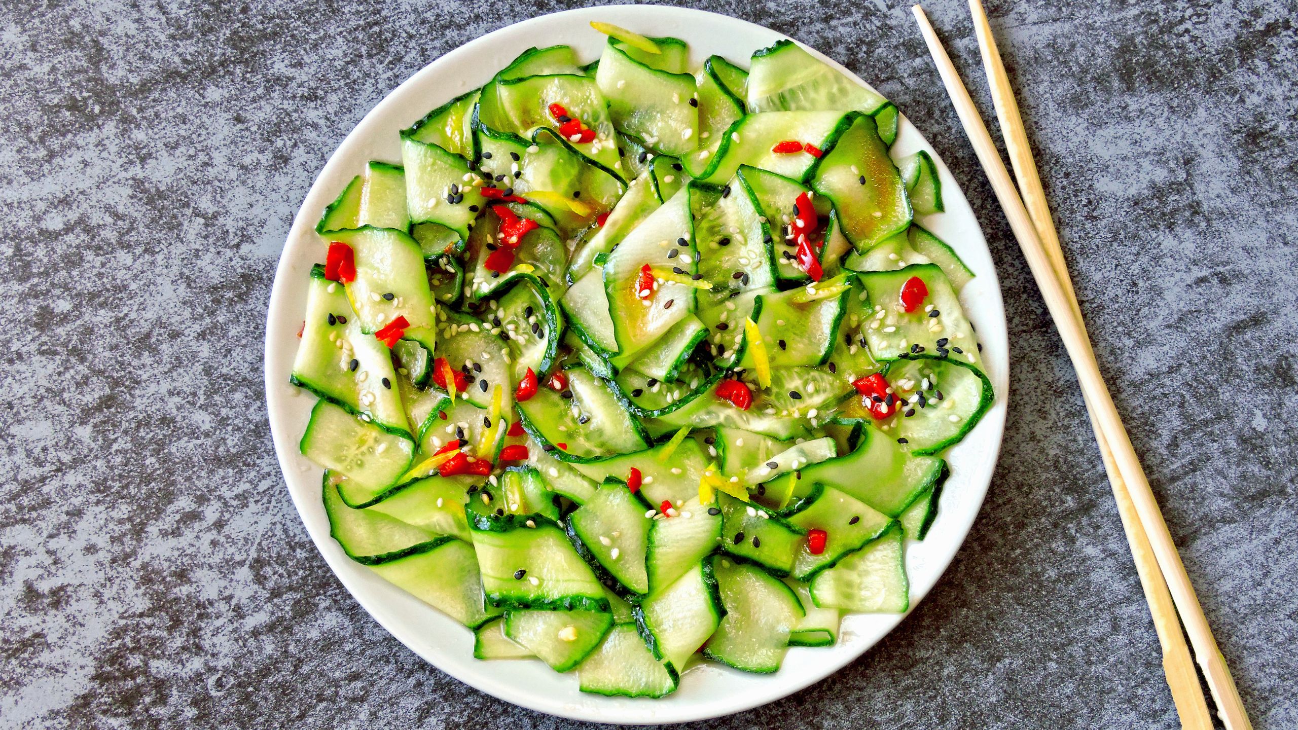 Ein Teller Chinesischer Gurkensalat mit Stäbchen neben dem Teller