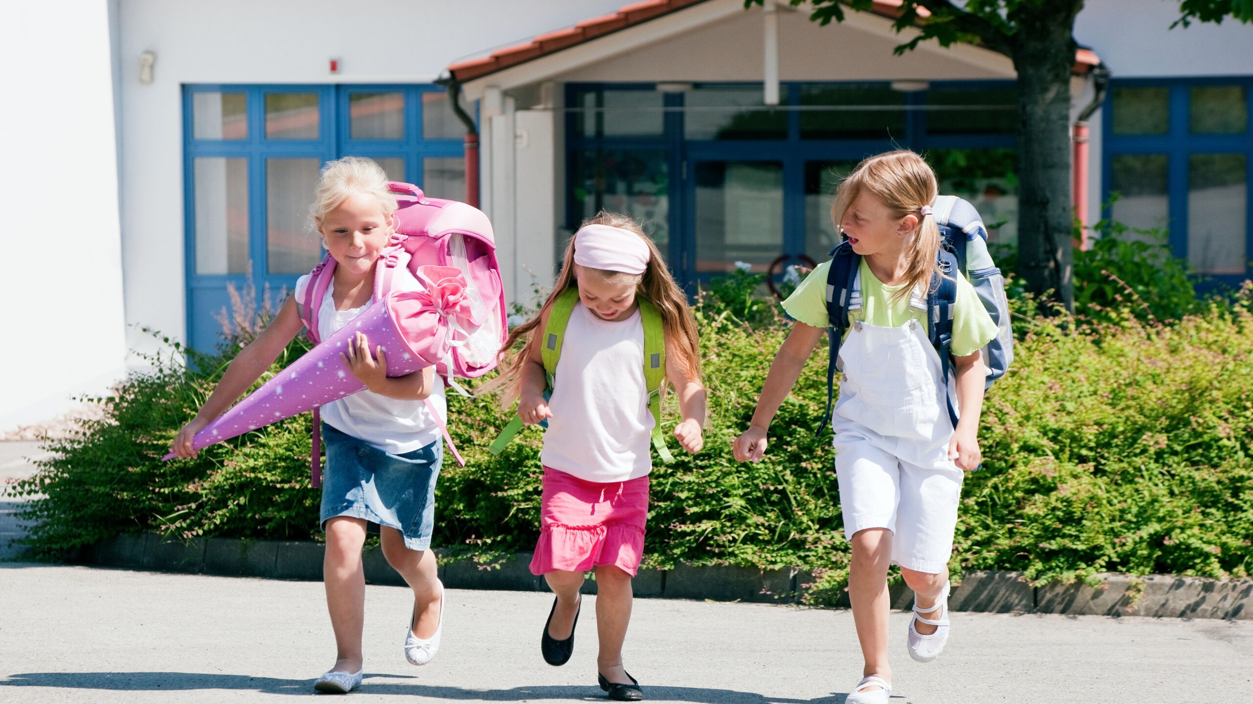 Drei Mädchen mit Schulranzen und eins davon mit einer Zuckertüte