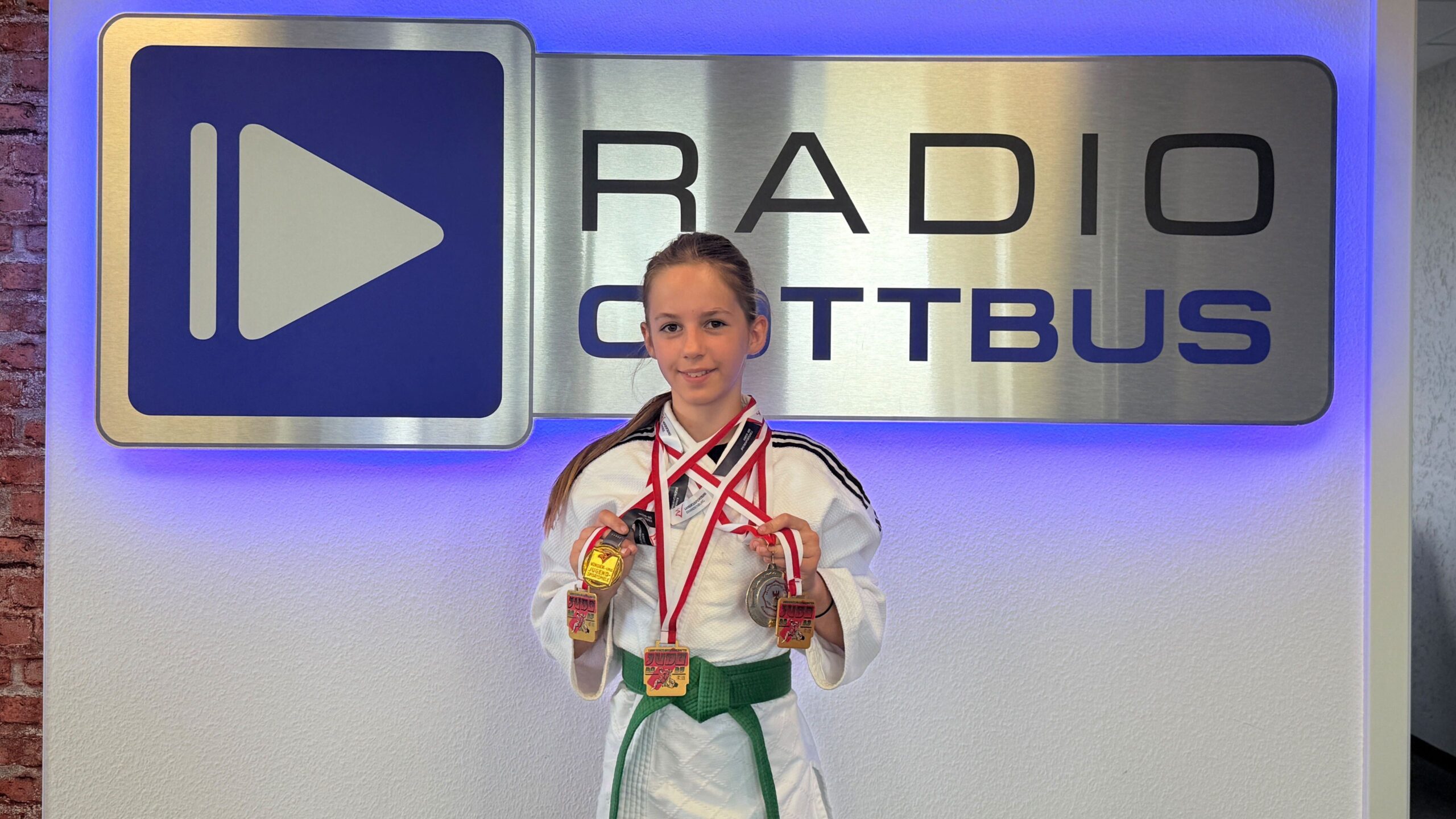 Fünffache Landesmeisterin im Judo Marie Rubik vor dem Radio Cottbus Logo