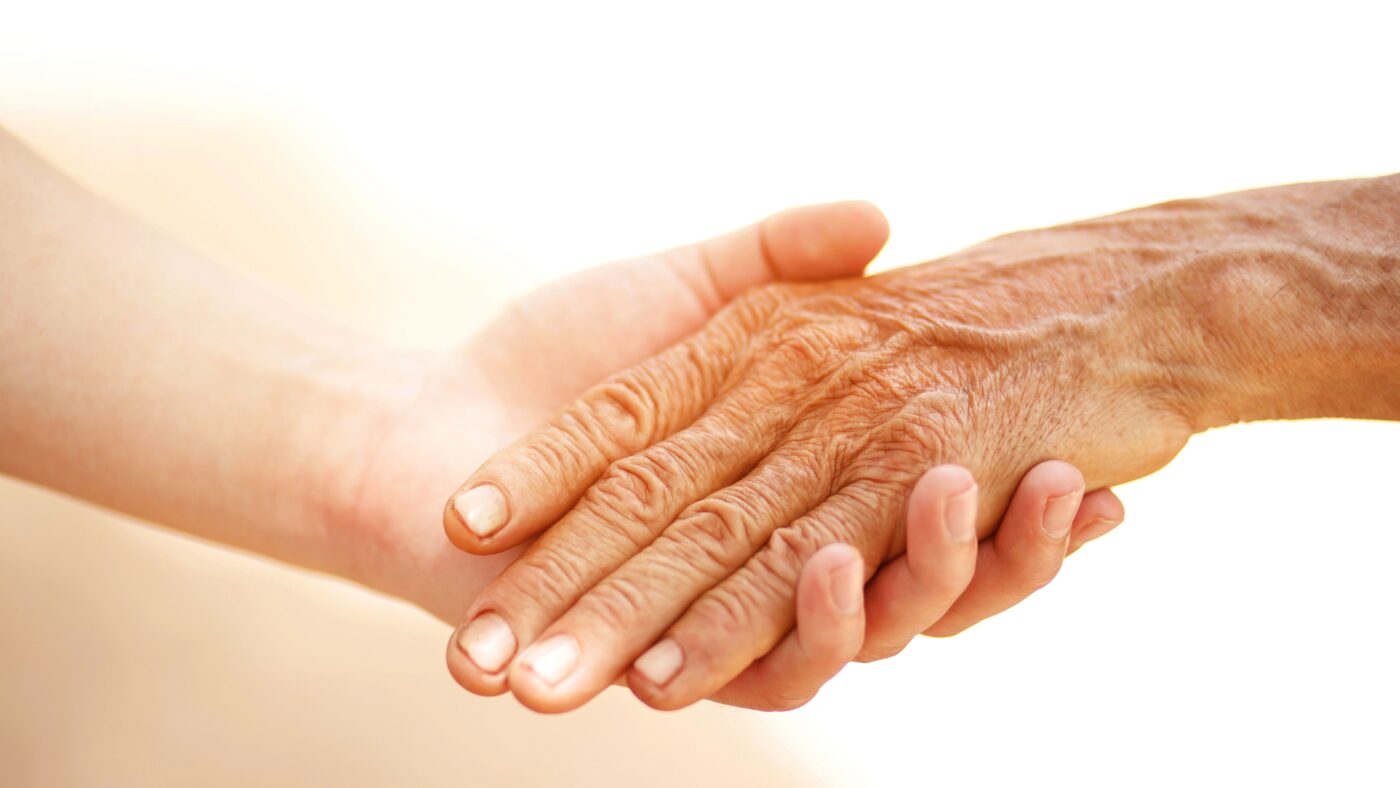 eine junge Hand und eine ältere Hand schlagen ein