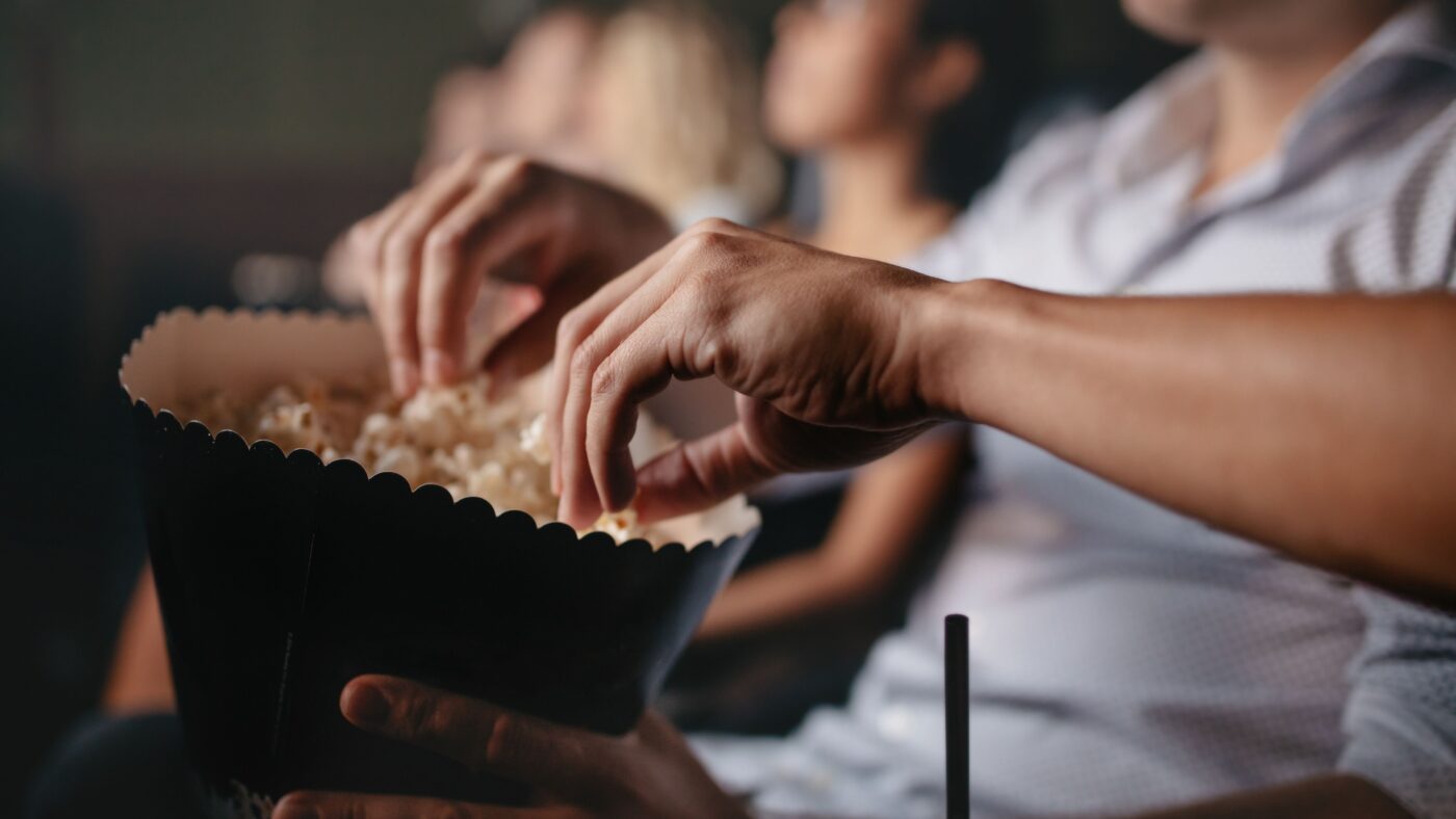 Mehrere Hände greifen in den Popcorneimer rein