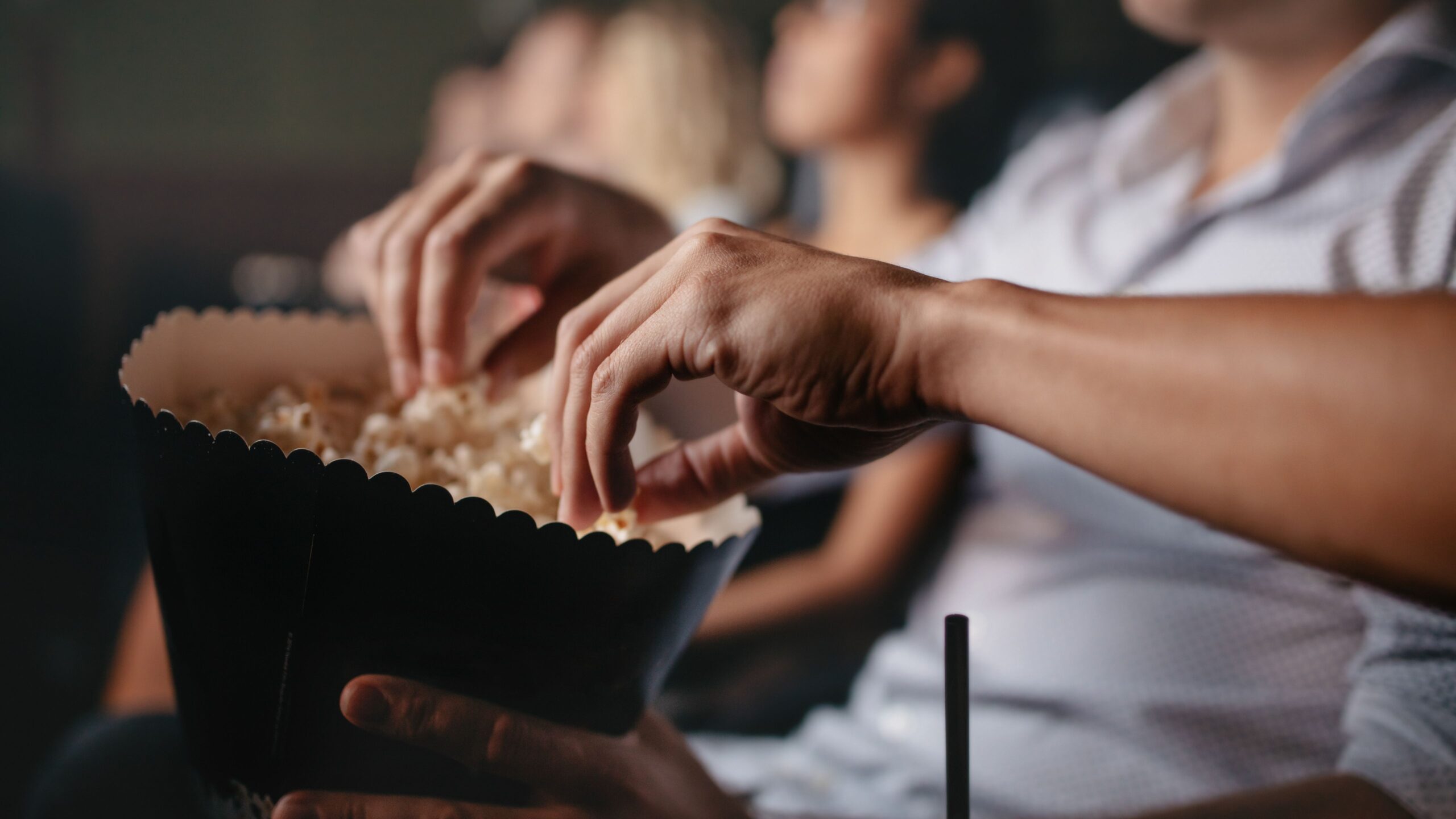 Mehrere Hände greifen in den Popcorneimer rein