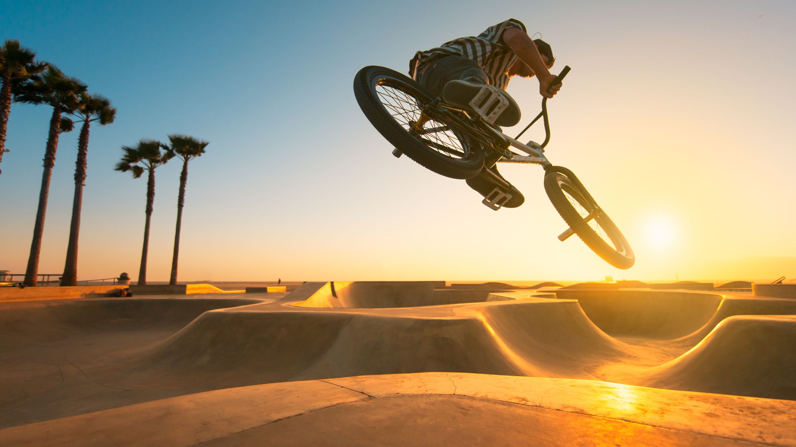 Auf dem Bild sieht man einen BMX Fahrer, der Tricks auf einer Rampe bei Sonnenuntergang macht