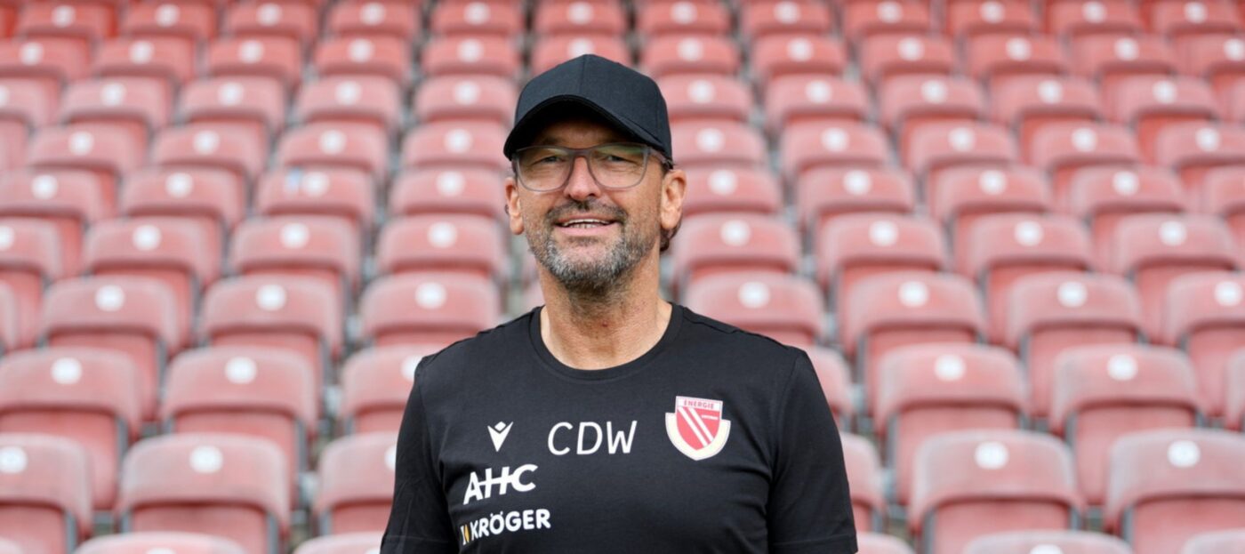Claus-Dieter Wollitz im Porträtfoto vor der Tribüne im LEAG Energie Stadion des FC Energie Cottbus vor der Saison 2025/26