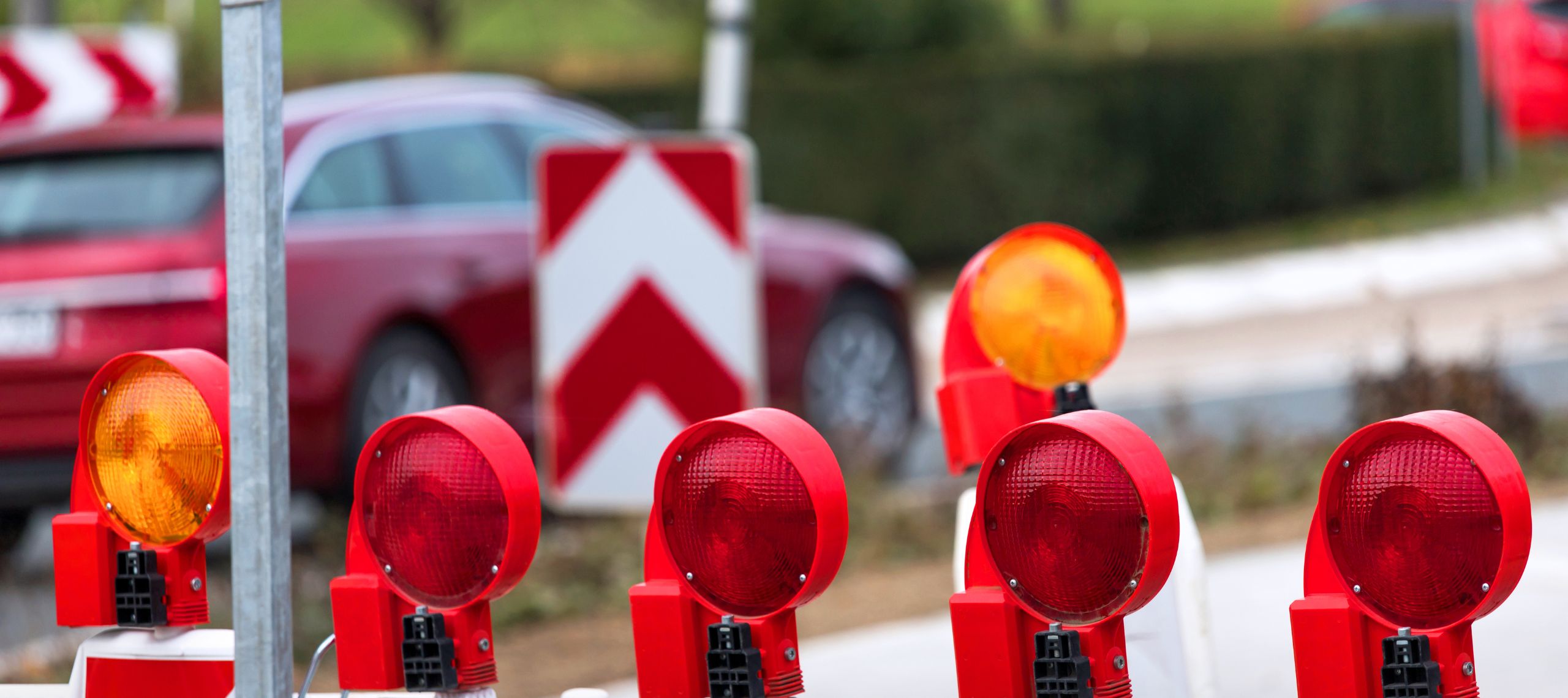 Ein durch ein Sperrschild und rote Lichter abgesperrte Straße vor einer Baustelle