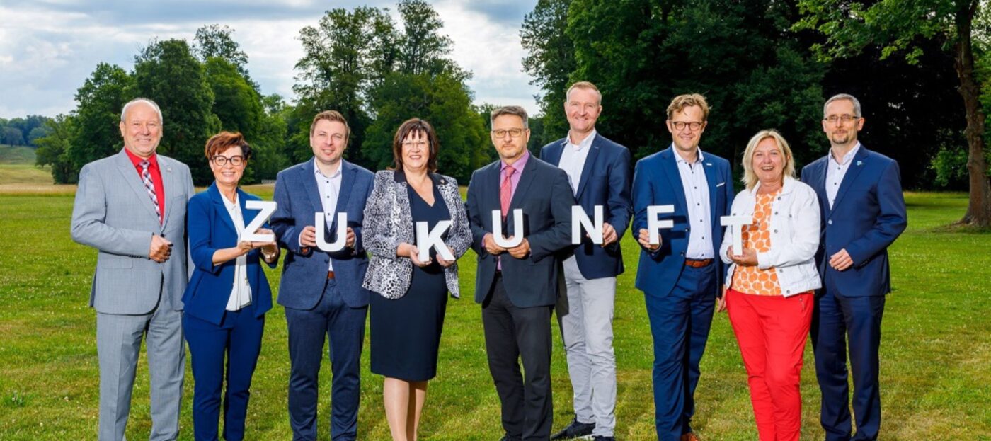 Die Teilnehmer der Lausitzrunde stehen auf einer Wiese in Bad Muskau und halten Buchstaben für das Wort Zukunft in den Händen