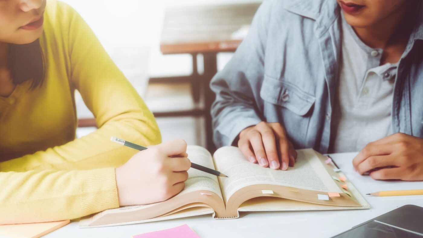 Zwei Personen die zusammen mit einem Buch lernen