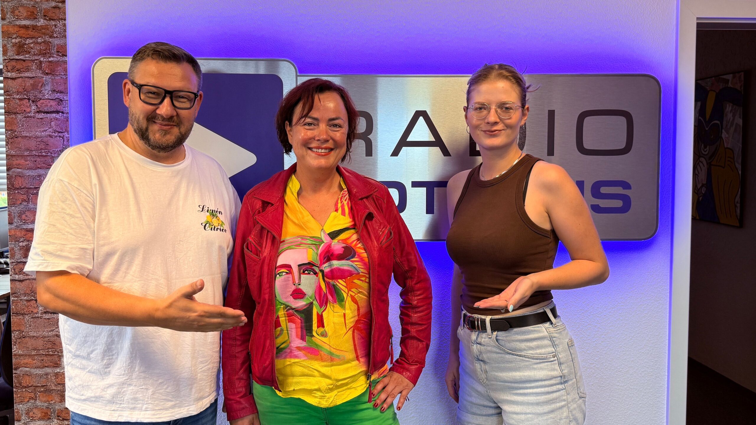 Die Wacher Macher Ronny Gersch und Luka Stadelmeier mit Mandy Sprejz vordem Radio Cottbus Logo