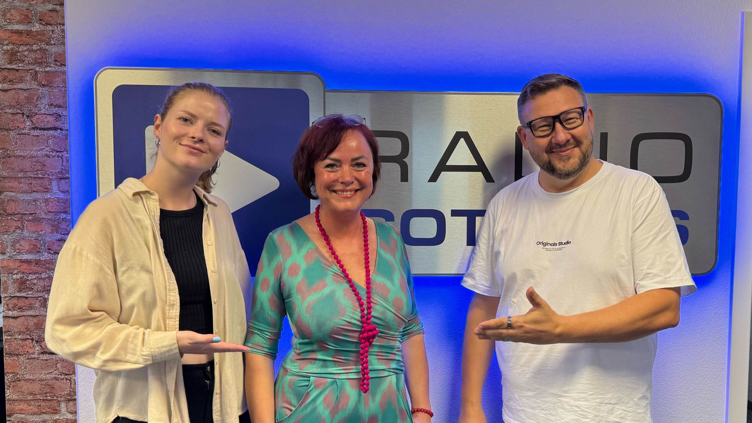 Mandy Sprejz und die Wacher Macher vor dem Radio Cottbus Logo im Studio