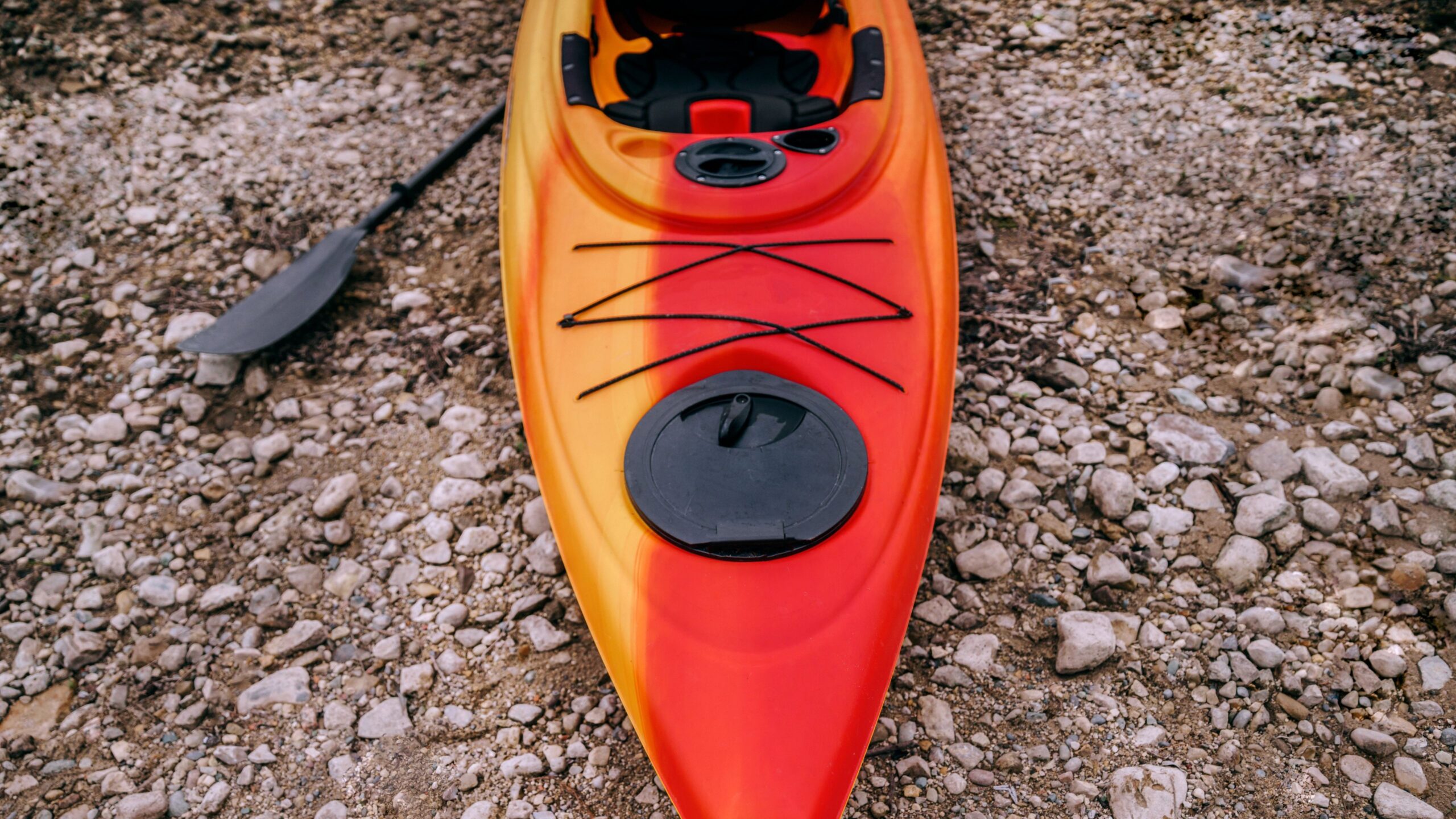 Ein rot-orangenes Kajak liegt auf einem Kieselstrand