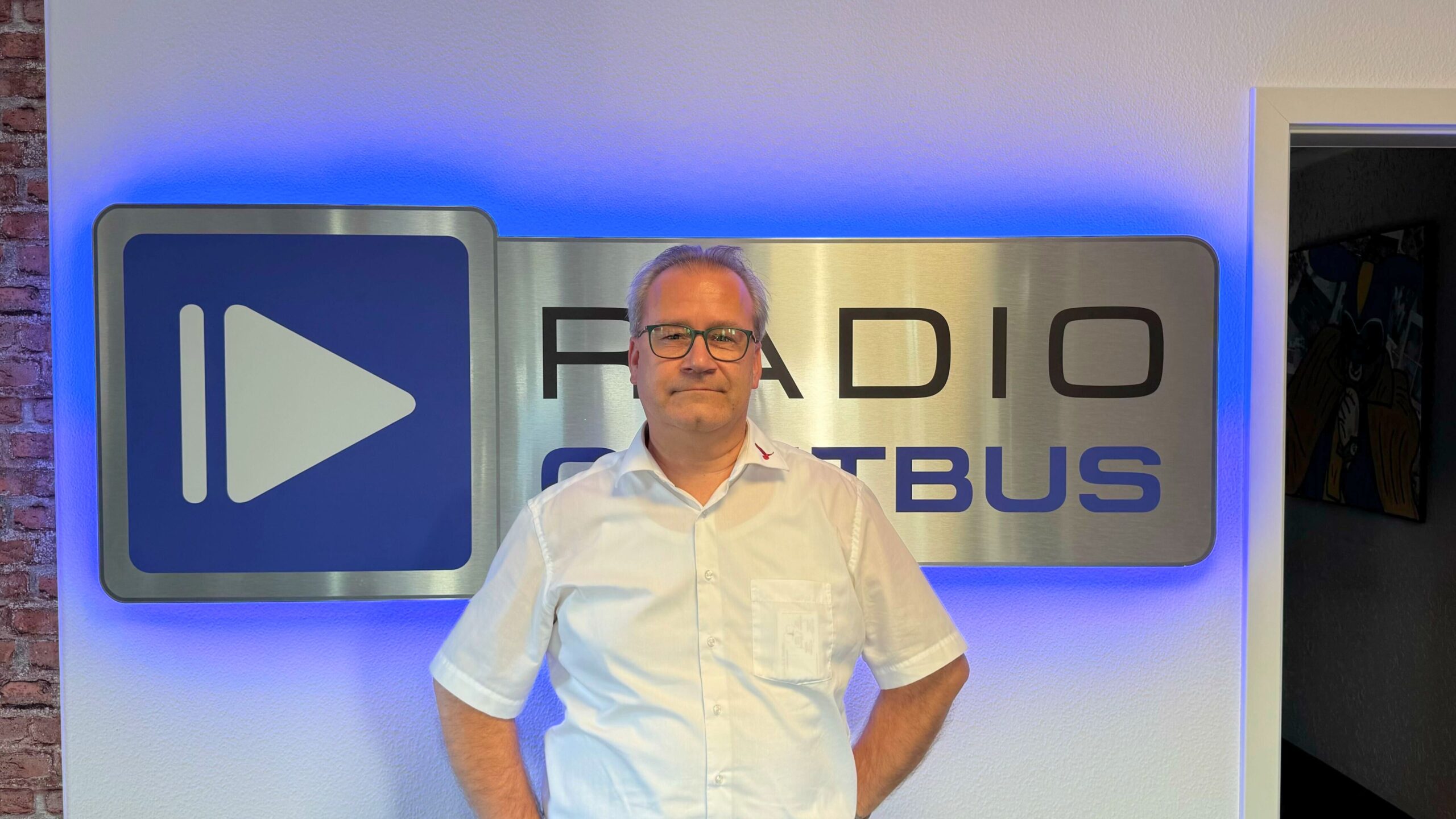 Roland Bartsch steht vor dem Radio Cottbus Logo