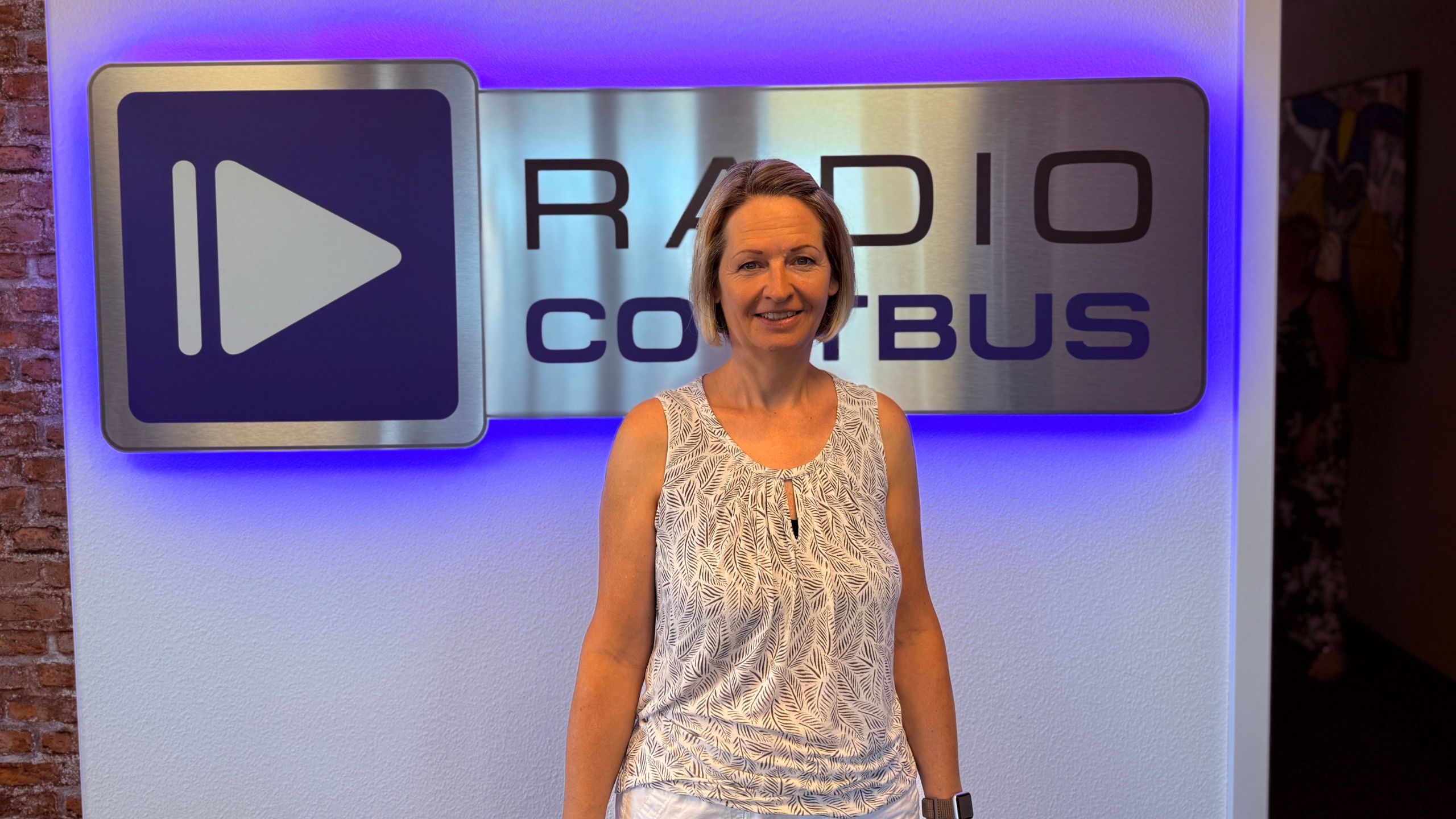 Sylvia Heinze vom Telekomshop im Gewerbepark Gallinchen vor dem Radio Cottbus Logo