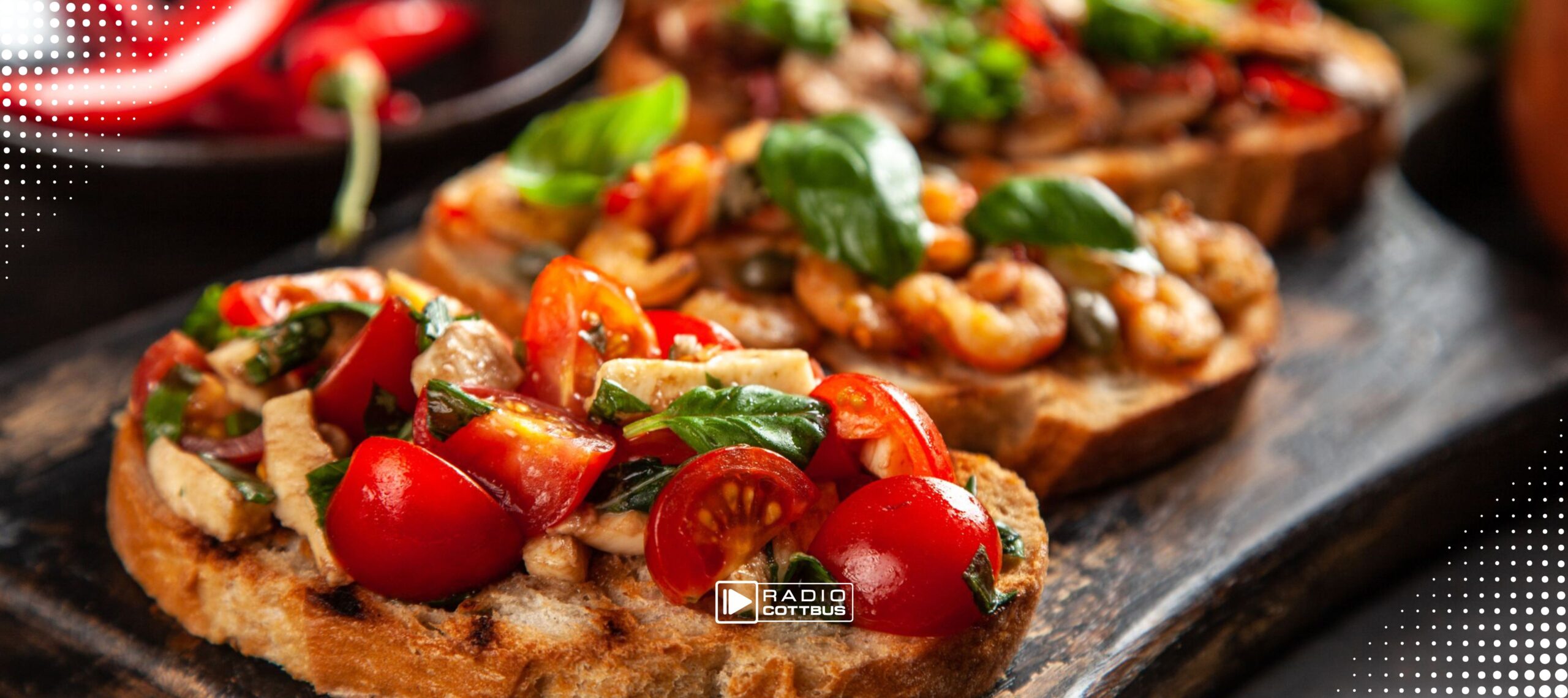 Bruschetta sind auf einem Teller sehr geschmackvoll angerichtet. Auf einem der Bruschetta sieht man Garnelen