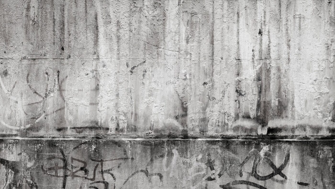 Eine graue Wand, auf der Grafitti zu sehen ist
