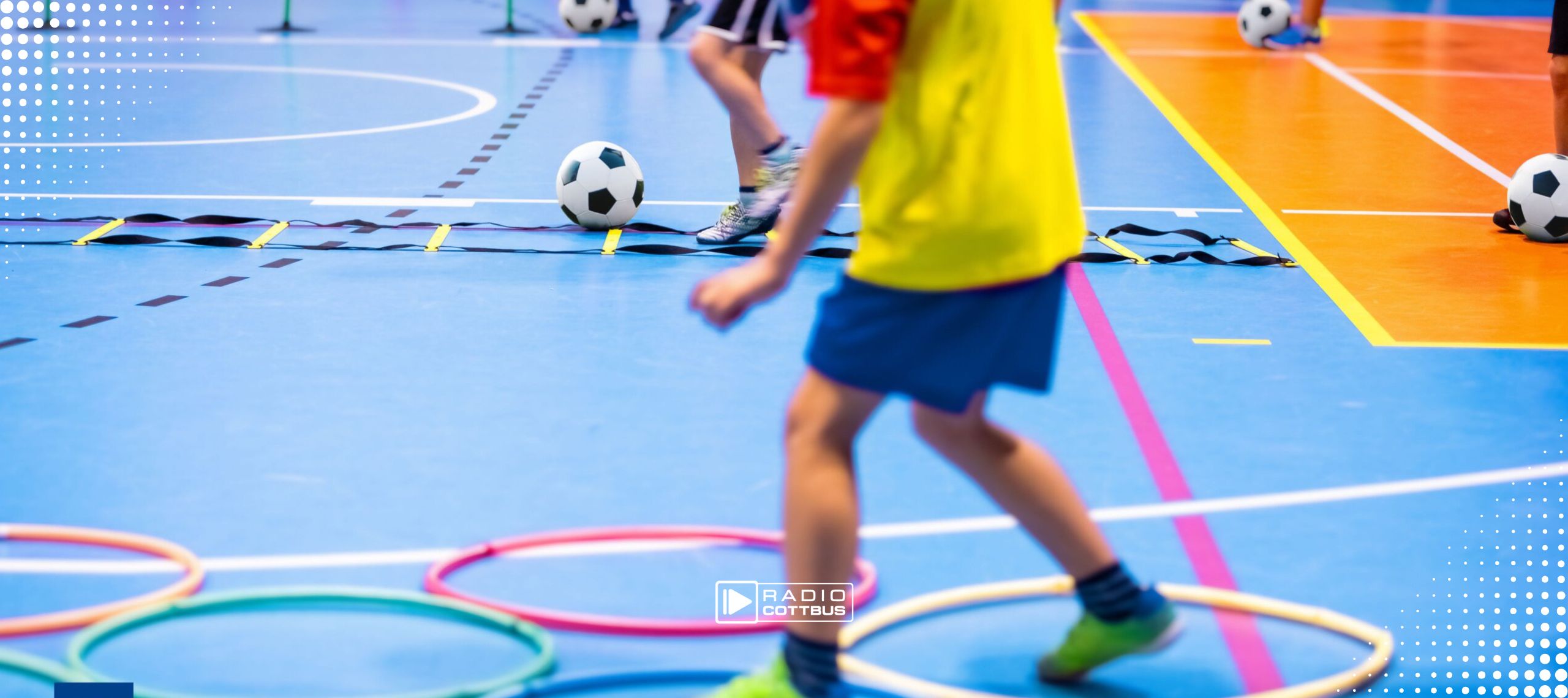 Kinder machen Sport in einer Halle und absolvieren einen Parcour mit Reifen auf dem Boden