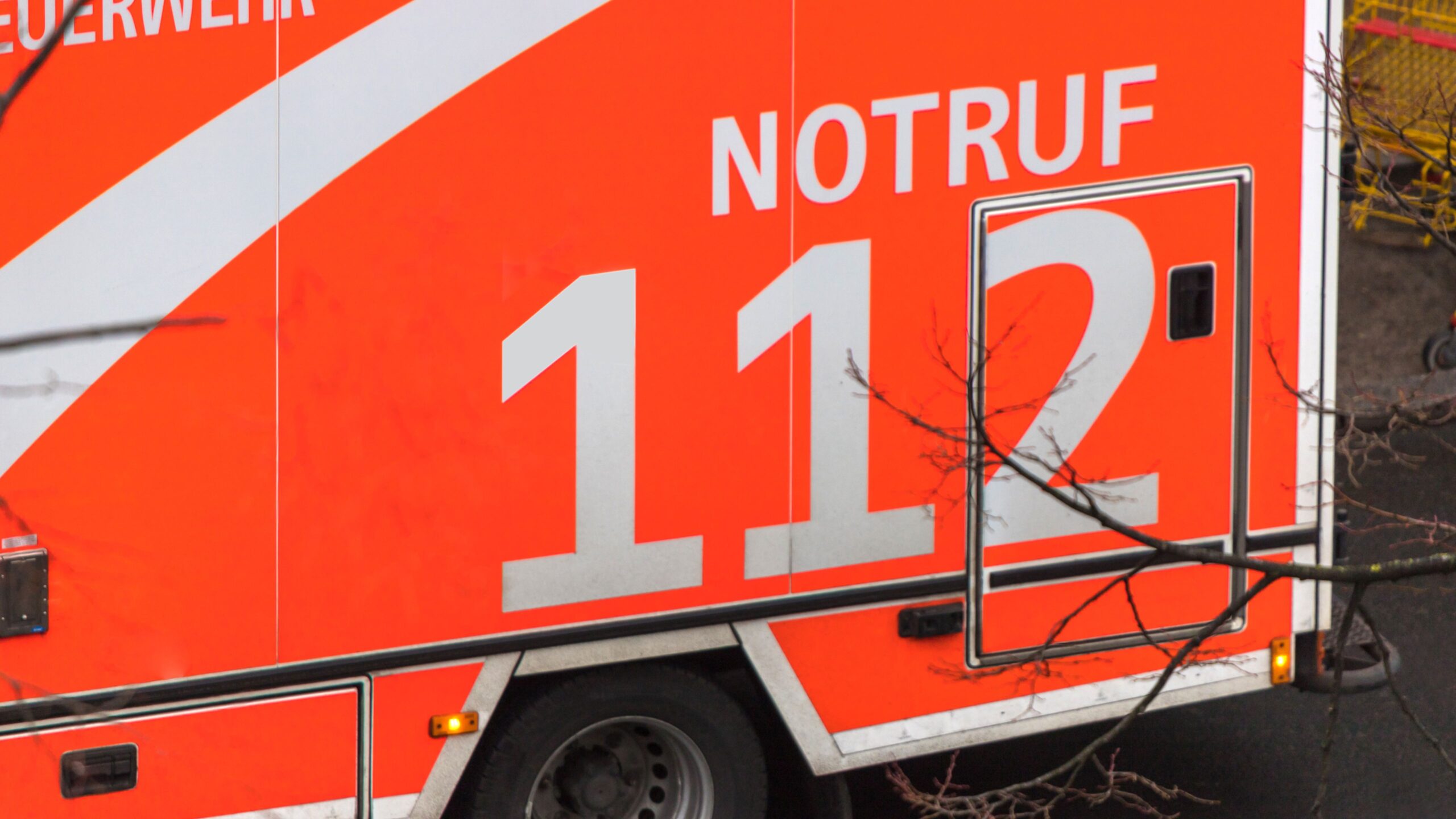 Ausschnitt eines orangefarbenen Einsatzfahrzeugs mit der Aufschrift Notruf 112