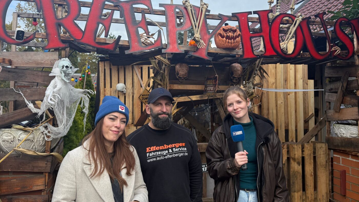 Moderatorin Luka Stadelmeier und die Macher vom Creepy House stehen vor dem Eingang des Creeyp House und lächeln in die Kamera