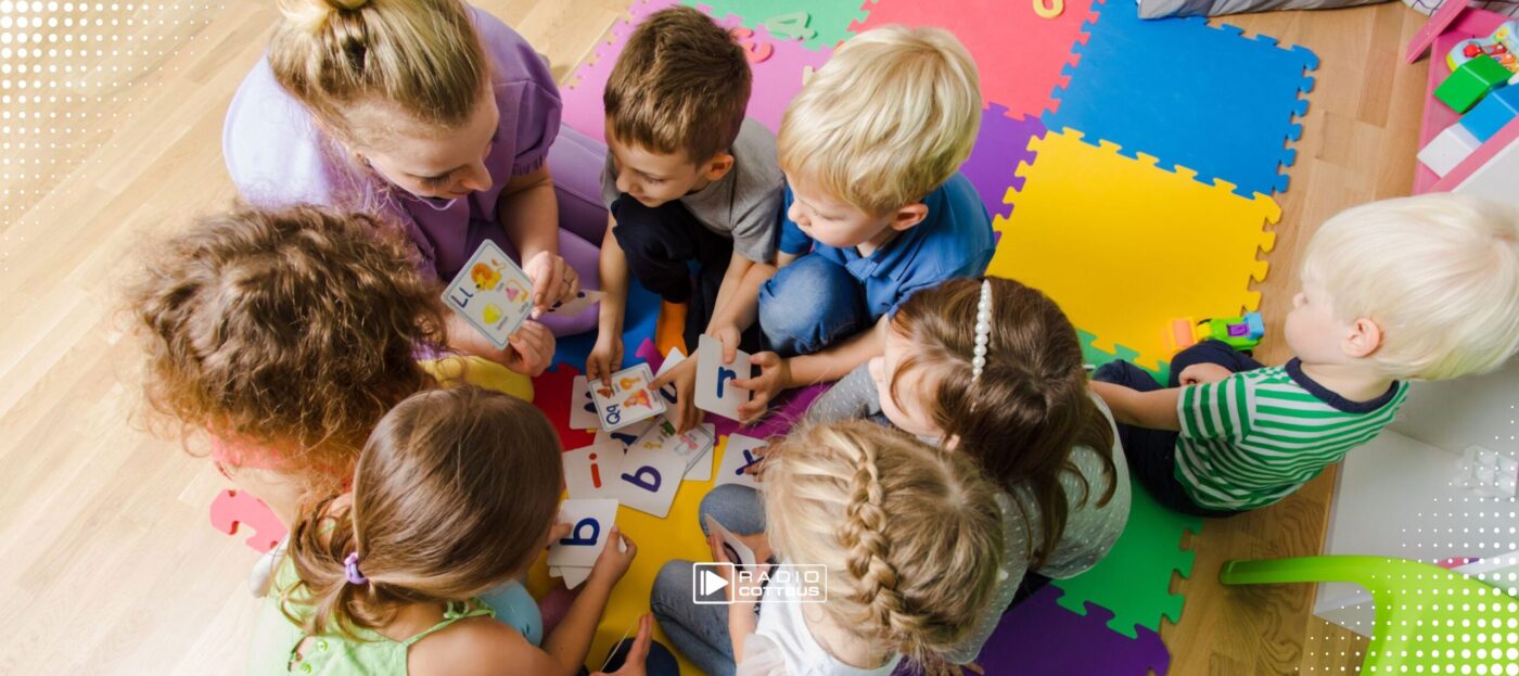 Kitakinder sitzen im Kreis auf dem Boden und spielen zusammen was, Blick von oben auf die Kinder
