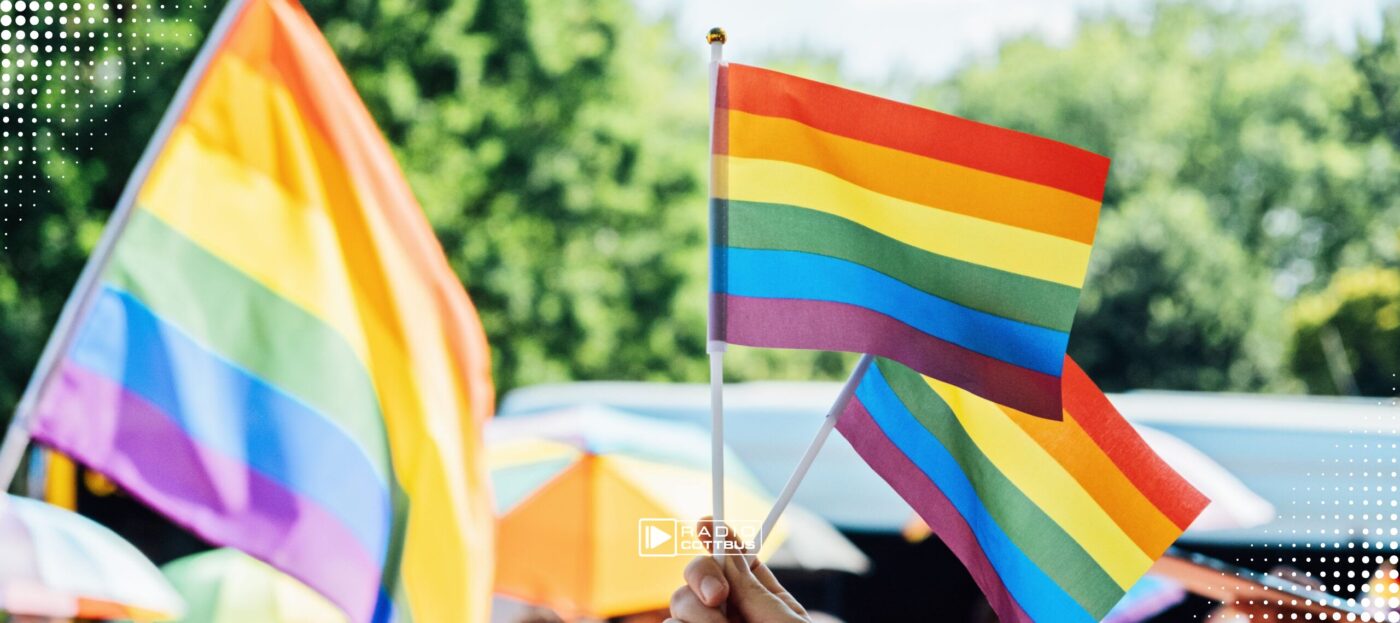 Eine Pride Demo mit mehreren Regenbogenflaggen