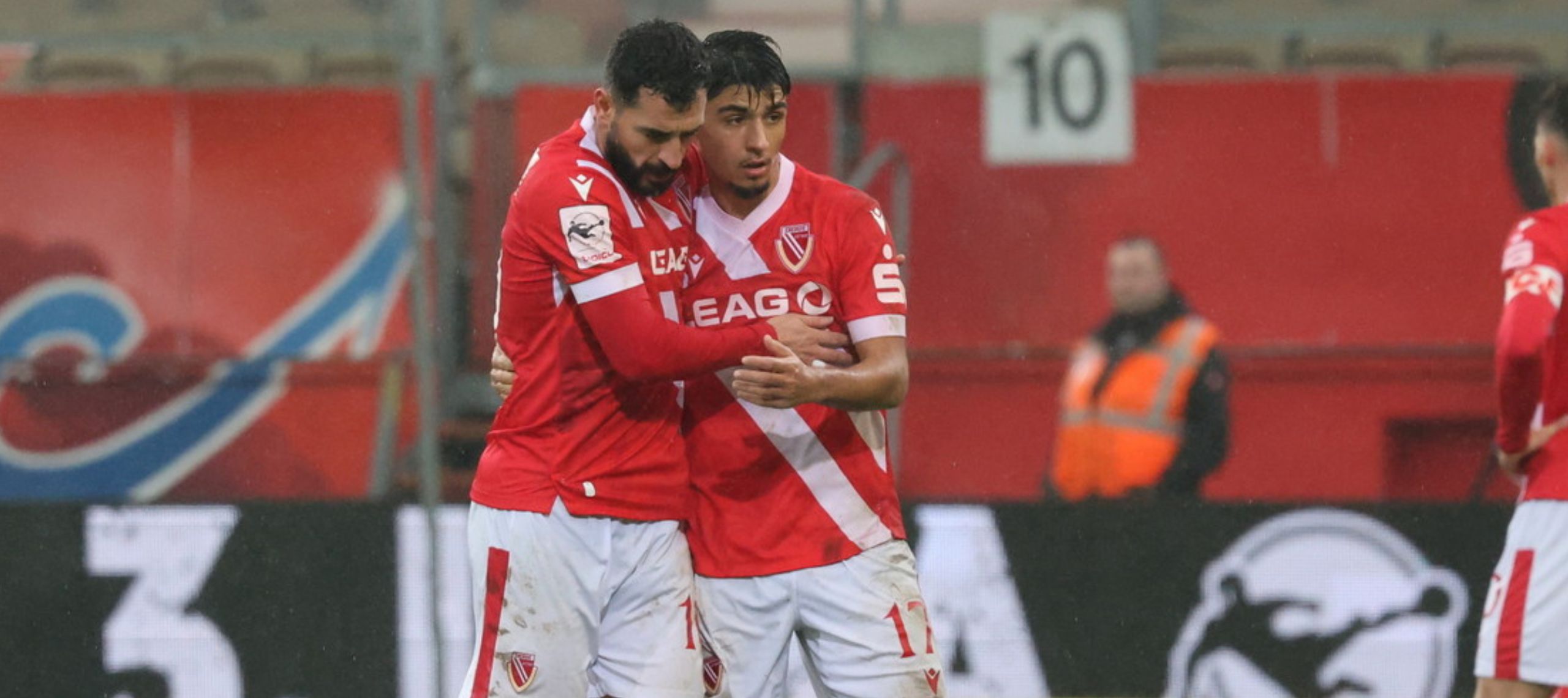 Tolcay Cigerci vom FC Energie Cottbus umarmt seinen Mannschaftskameraden Can Moustfa nach dem Sieg gegen Alemannia Aachen auf dem Rasen im Stadion des LEAG Energie Stadions
