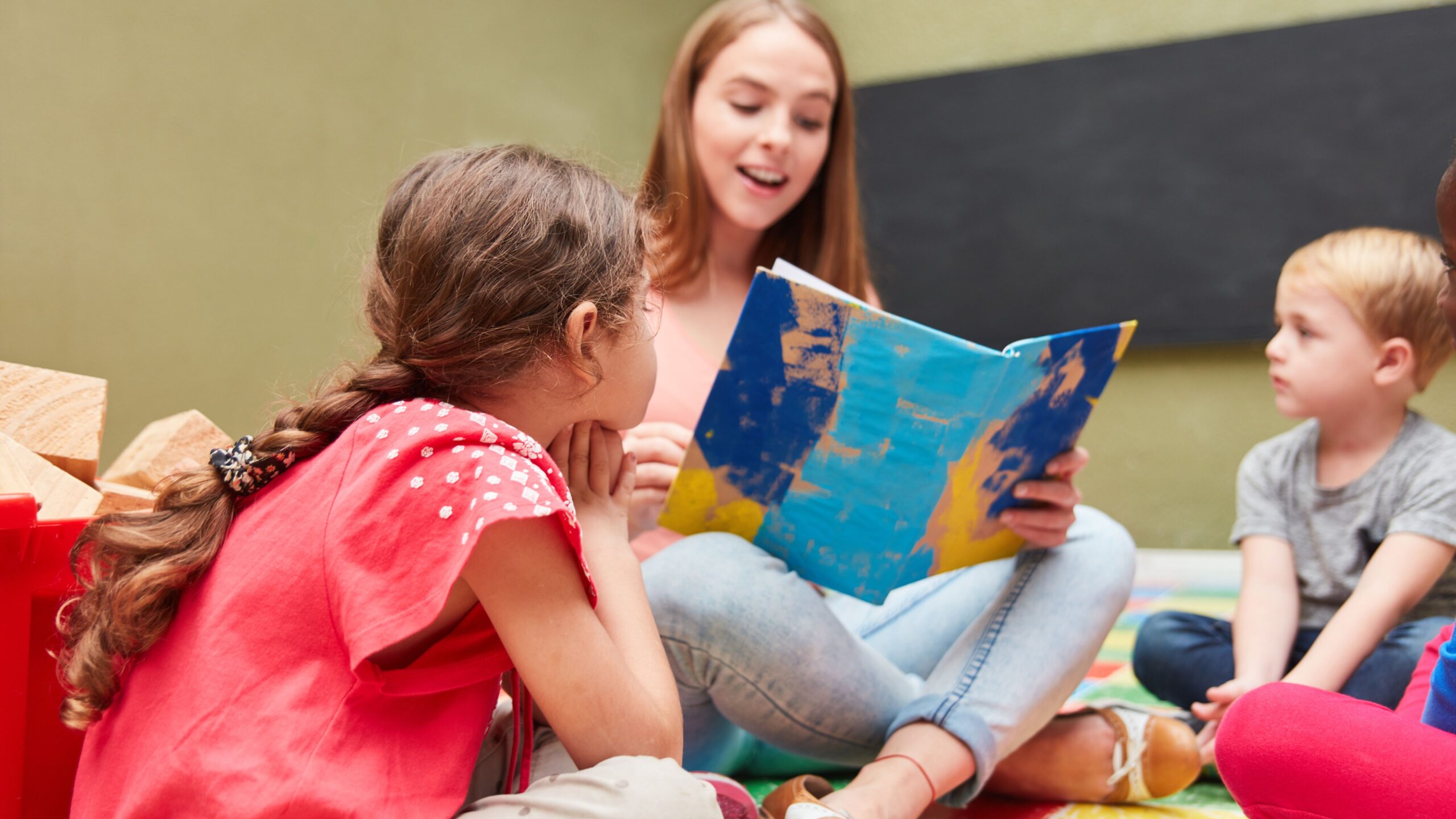 Eine Frau liest zwei Kindern aus einem Buch vor