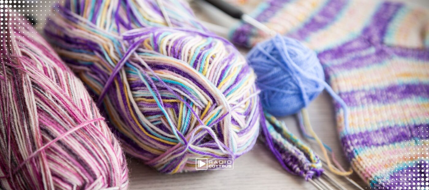 Gestrickte bunte Socken und Wolle liegen auf einem Holztisch