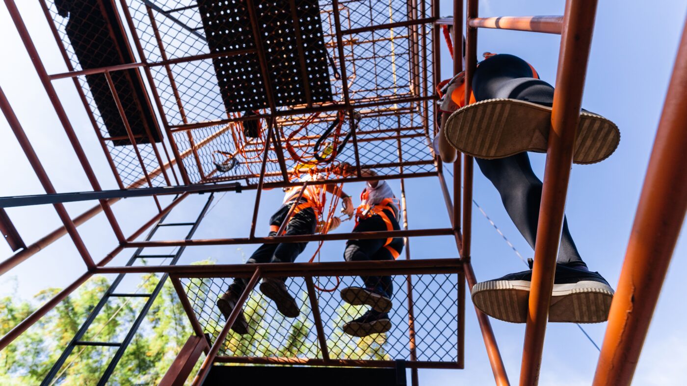 Drei Männer von unten auf einem Gerüst fotografiert