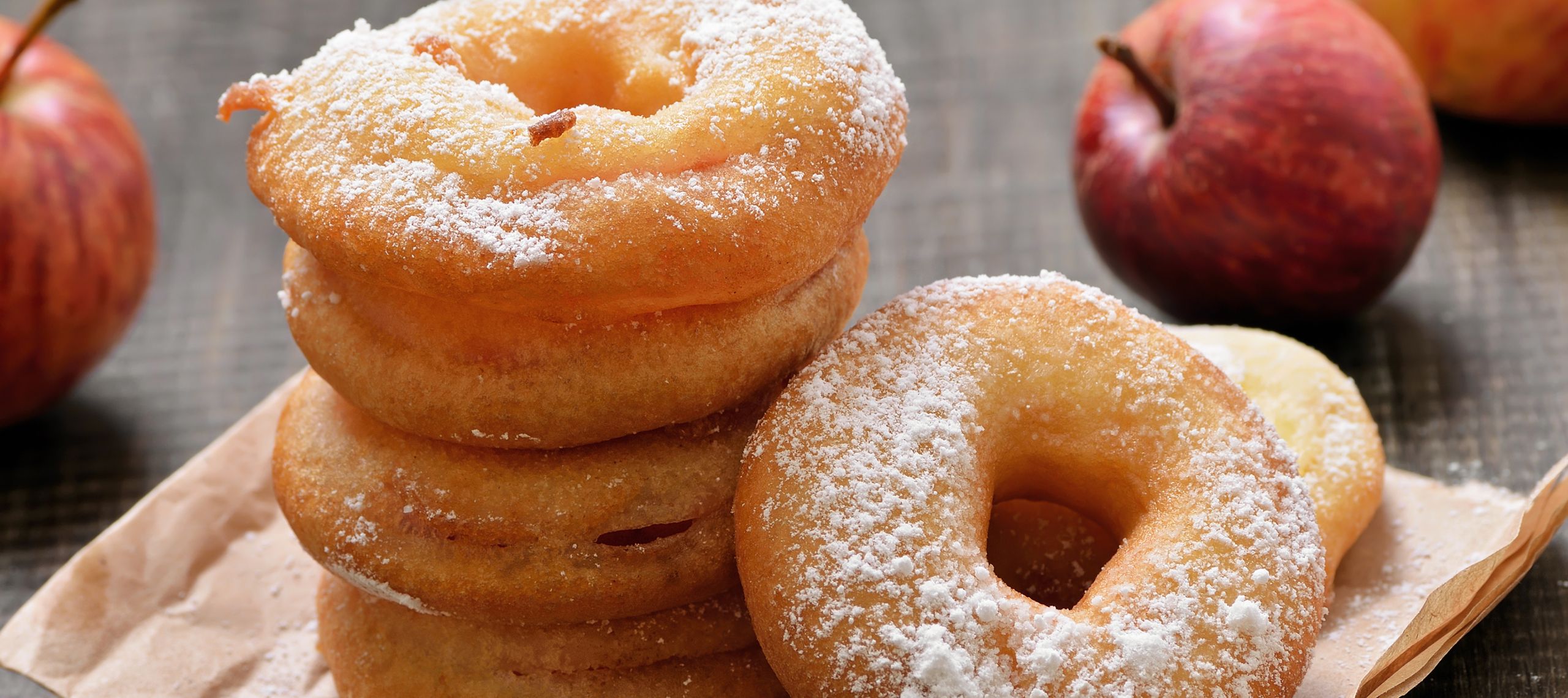 Frische Apfelringe liegen gebacken und gestapelt auf einem Teller mit Backpapier