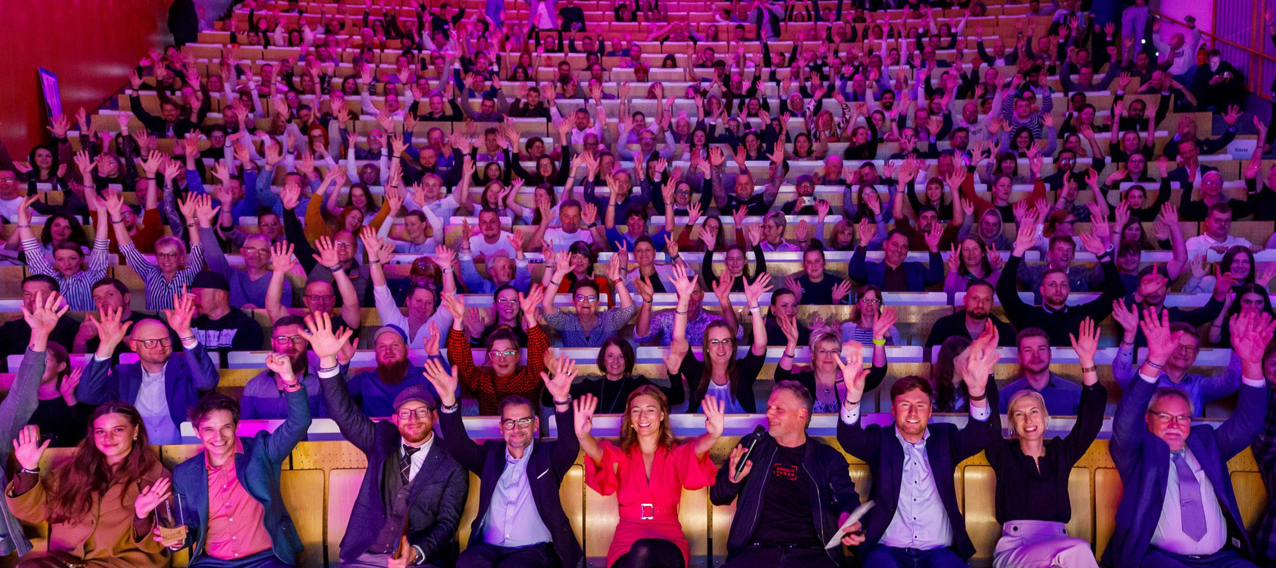 Das Publikum der Starparade 2025 - dem Gründer- und Innovationspreis in der Lausitz winkt begeistert in die Kamera aus dem Audimax der BTU Cottbus-Senftenberg