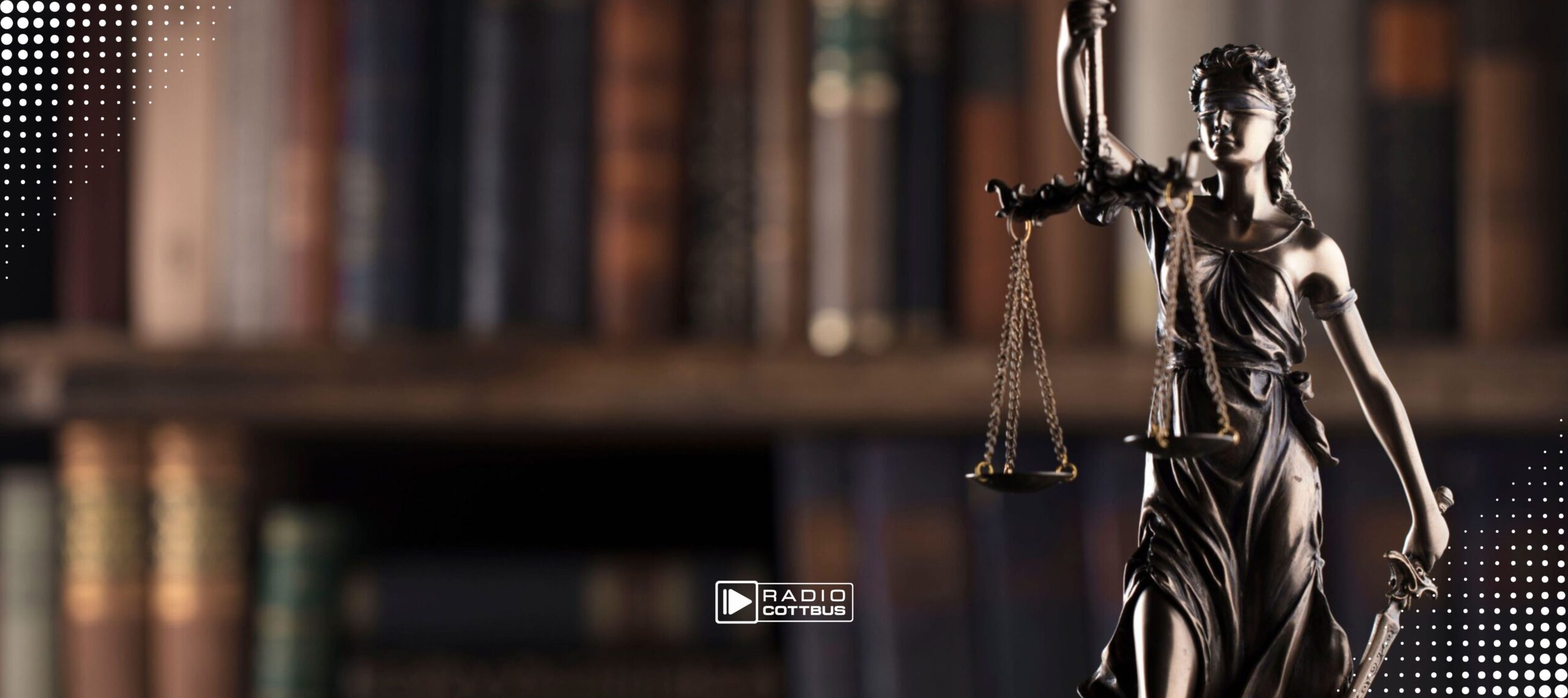 Eine Bronzefigur der Justizia vor einem unscharfen Bücherregal