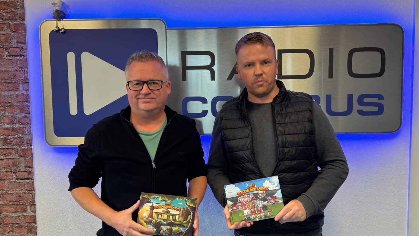 Enrico Schnick und Jörg Schröter halten das Buch "Die Bademuesel" vor dem Radio Cottbus Logo hoch.