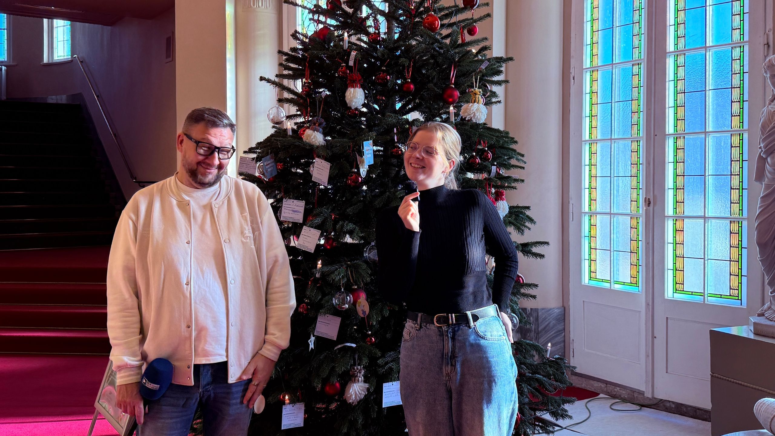 Wunschbaumaktion im Staatstheater Cottbus. Ronny Gersch und Luka Stadelmeier stehen vor der Wunschbaum im Staatstheater
